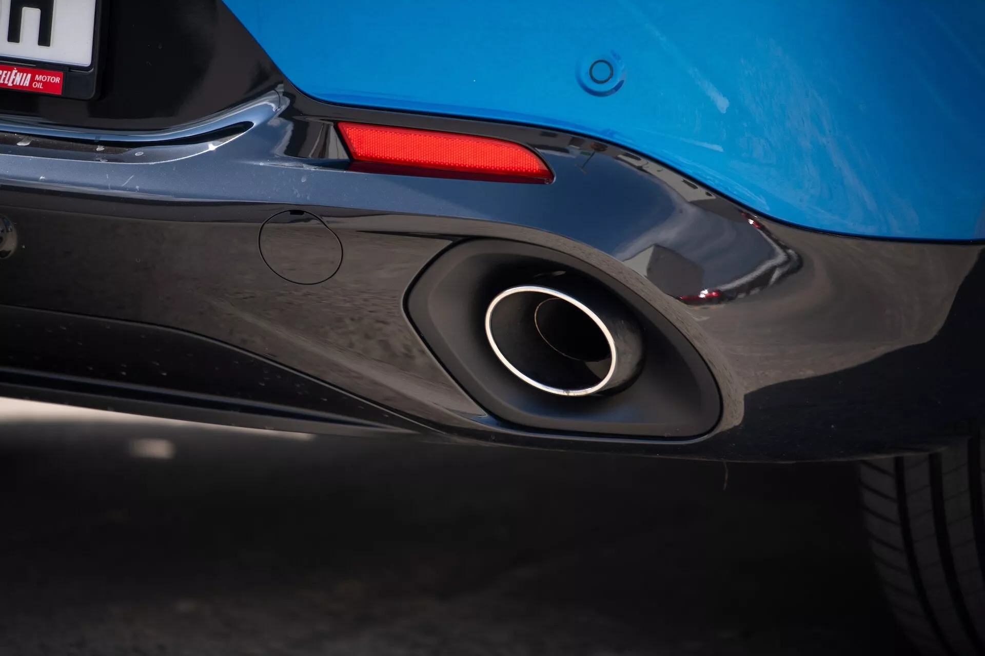 Detailní pohled na zadní část Alfa Romeo Tonale 2022 s důrazem na sportovní výfukovou trubku, aerodynamický design zadního nárazníku a modrou barvu karoserie s náznakem zadního světla