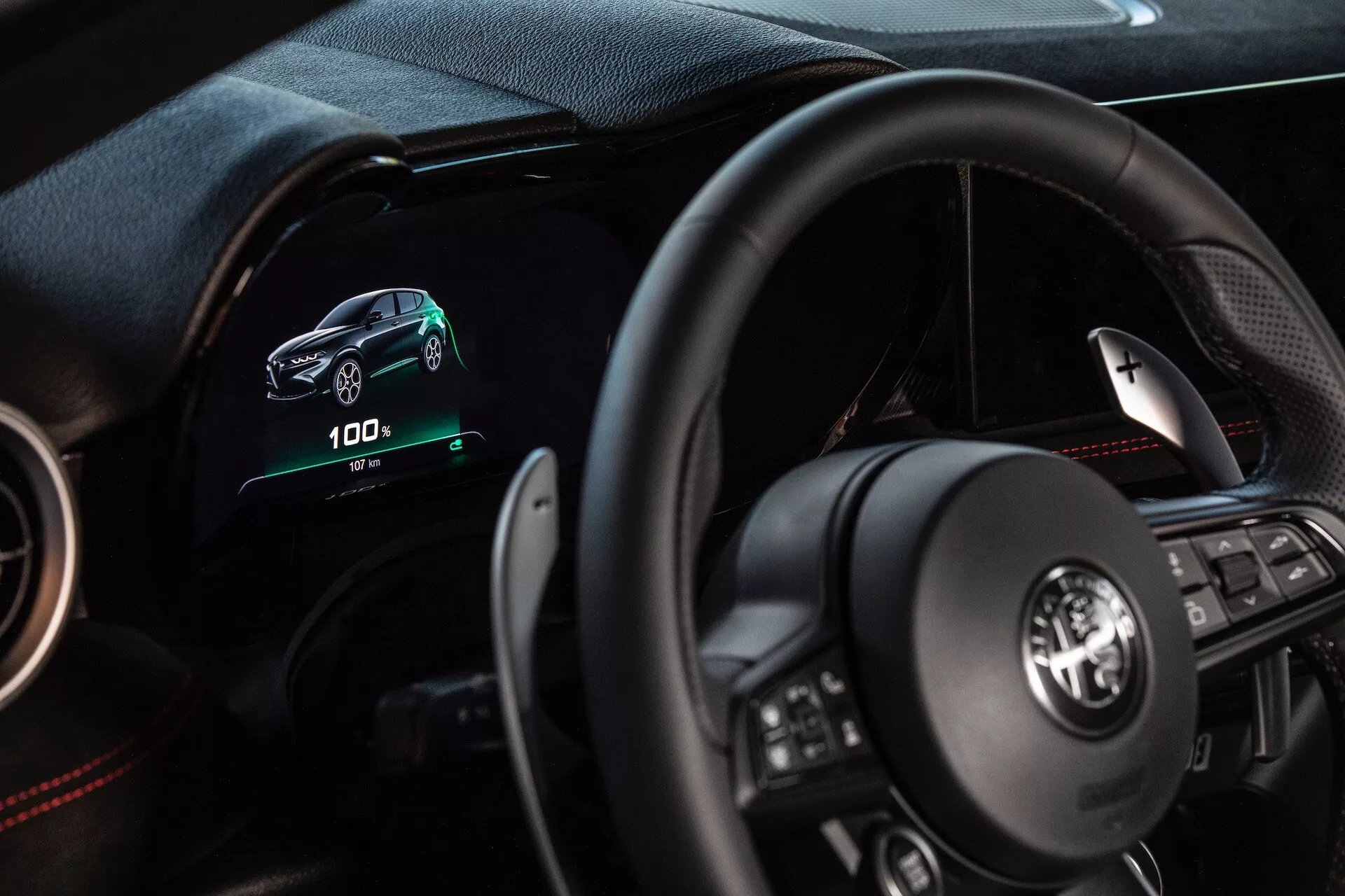 Interiér Alfa Romeo Tonale 2022 z pohledu řidiče s digitálním palubním počítačem, multifunkčním volantem a indikátory elektrického vozidla