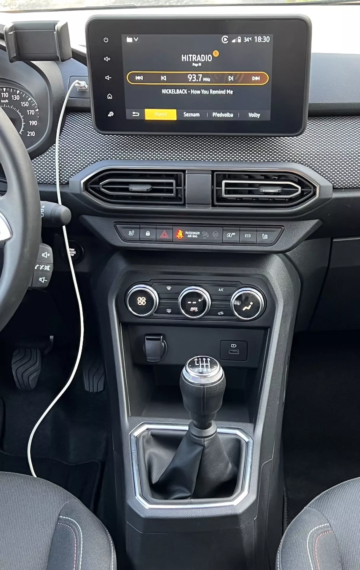 Interiér Dacia Jogger 2022 se zaměřením na středovou konzolu a palubní desku, s plovoucím dotykovým displejem infotainmentu, vzduchovými výdechy, ovládáním klimatizace a vozidla a manuální převodovkou