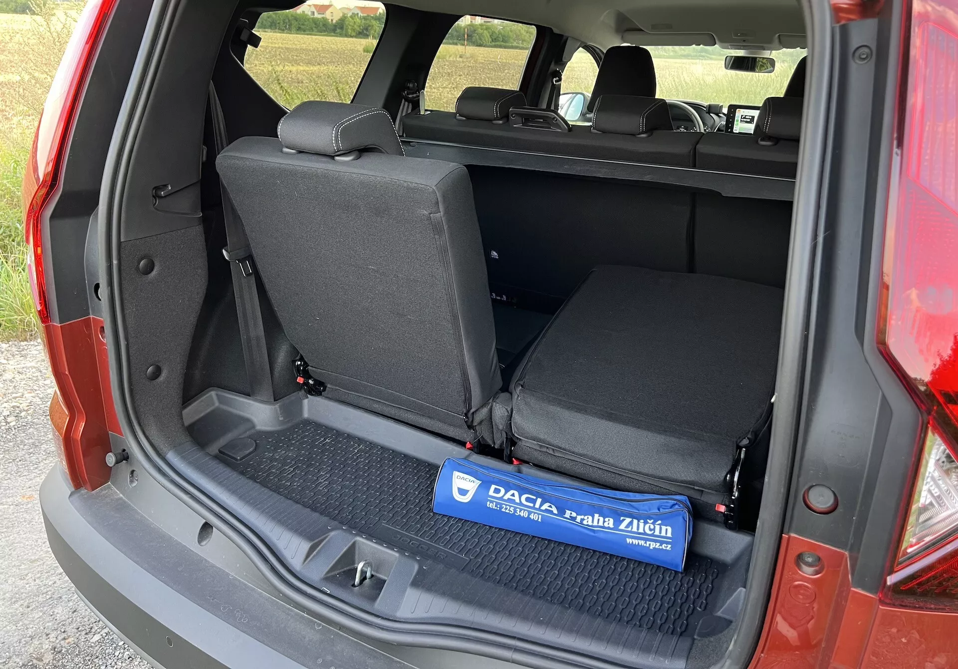 Interiér Dacia Jogger 2022 zobrazený z leva s otevřeným kufrerem, zobrazující plochou nákladovou plochu s gumovou podložkou, zadní sedadla dělená v poměru 60/40 a boční lišty bez viditelných pokročilých technologií nebo luxusních komponentů