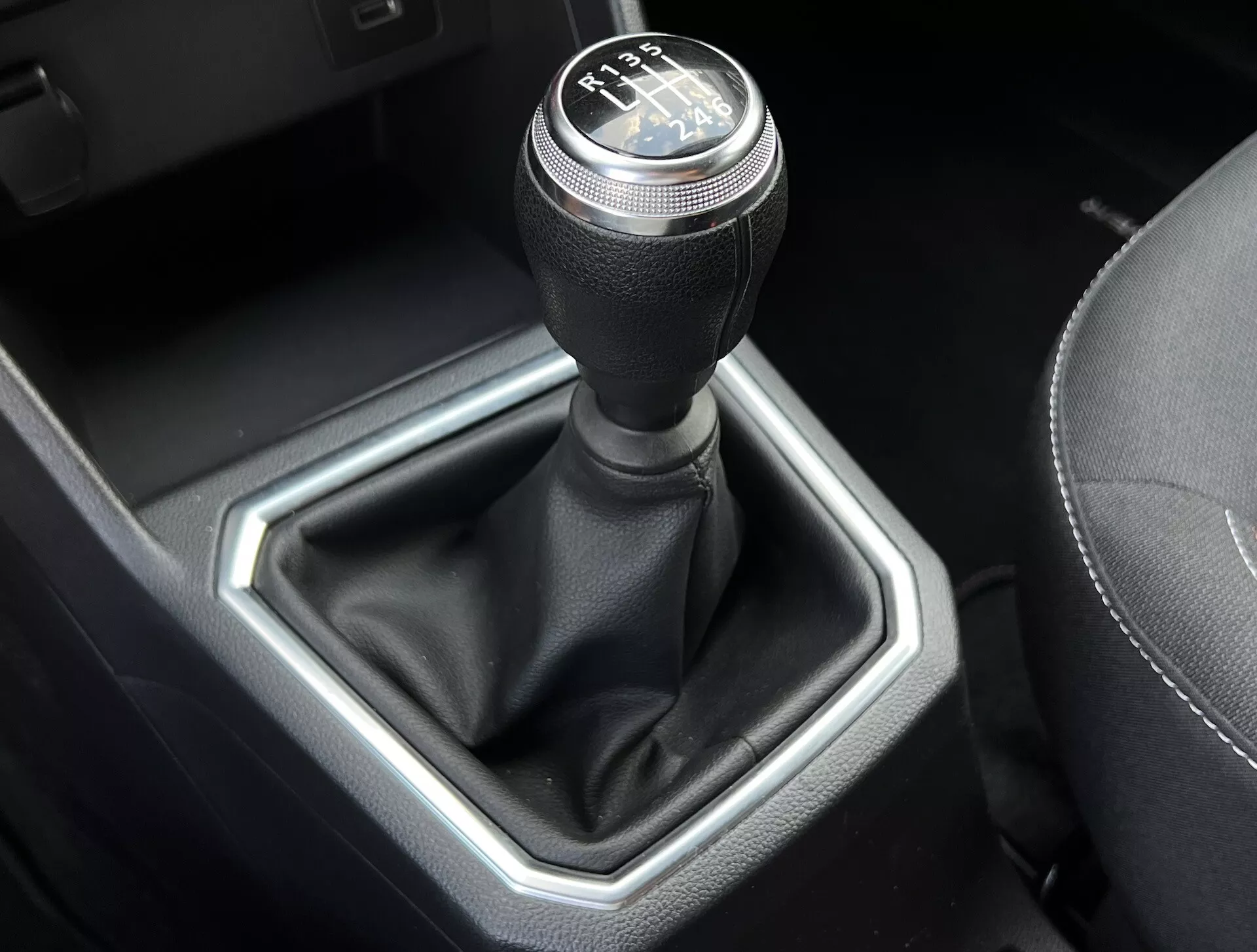 Detailní pohled na manuální převodovku Dacia Jogger 2022 s 6rychlostním schématem řazení, koženým krytem páky a kovovou šestiúhelníkovou vložkou ve vysoce kvalitním interiéru vozidla