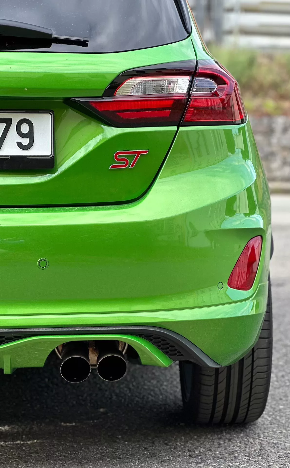 Detailní pohled na zadní část Ford Fiesta ST 2022 v jasně zelené metalíze, zvýrazňující LED zadní světla, dvojitou chromovanou výfukovou soustavu a aerodynamický zadní difuzor