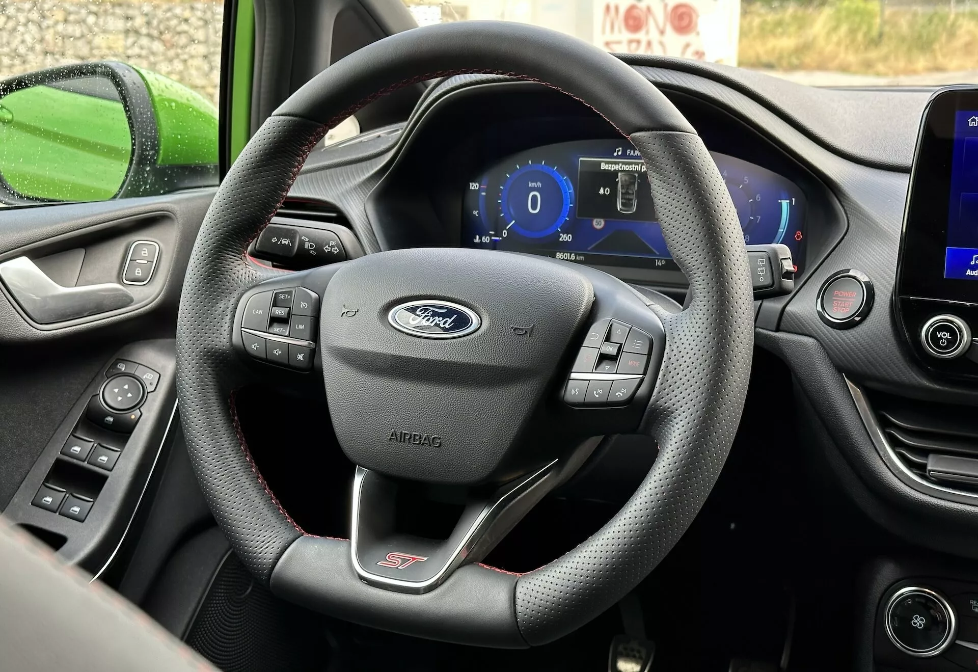 Interiér Ford Fiesta 2022 zaměřený na kožený volant s třemi paprsky s multifunkčními ovládáními a digitálním palubním panelem z perspektivy řidičova sedadla