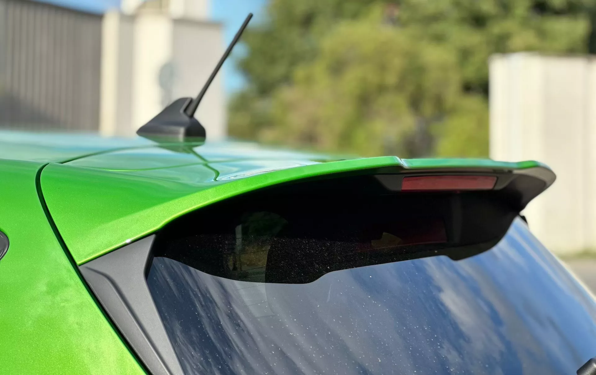 Detailní záběr na zadní část Ford Fiesta 2022 s důrazem na spojler aftermarket, sytě zelenou barvu a integrované třetí brzdové světlo