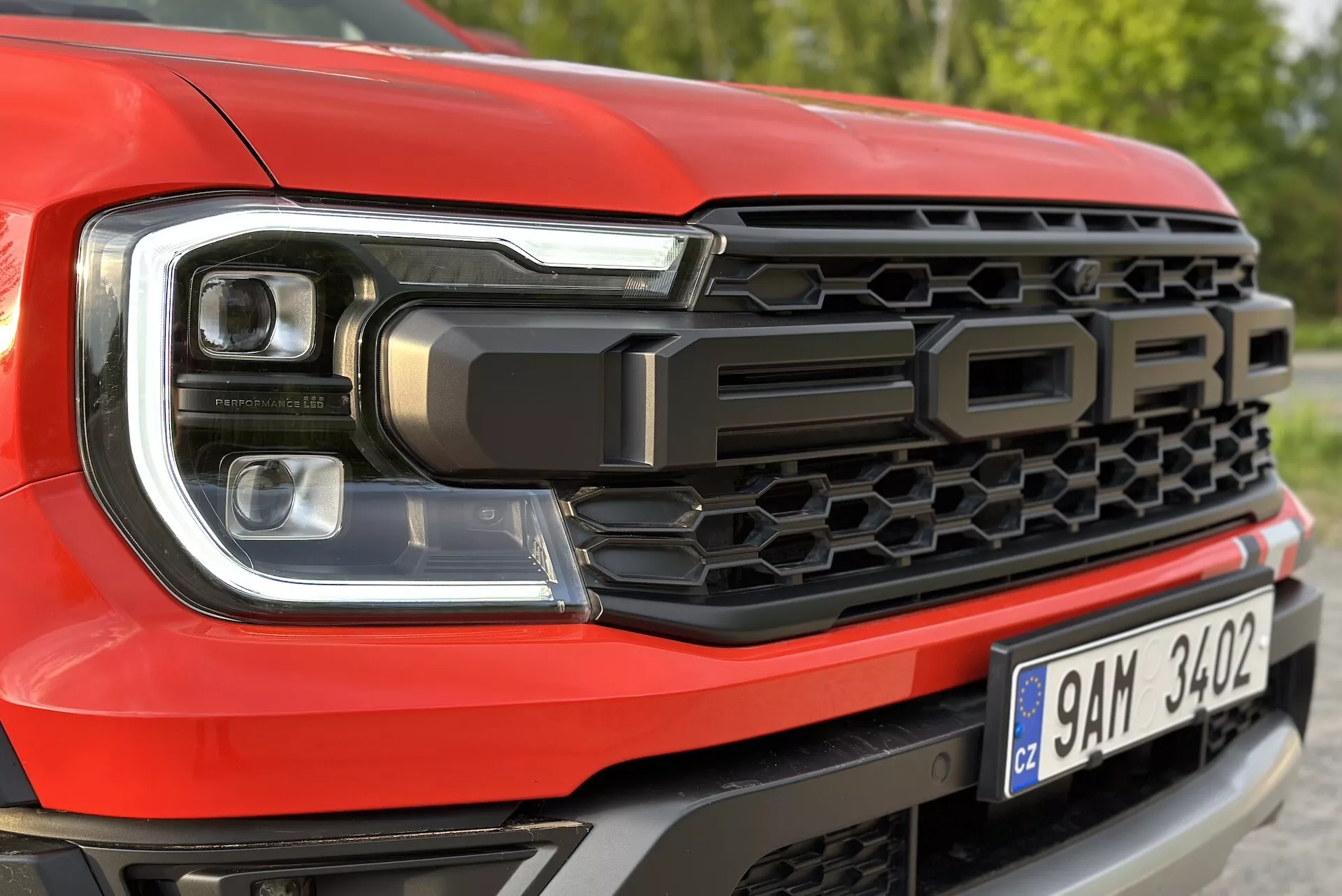 Detailní záběr na přední levou stranu Fordu Ranger 2022, zvýrazňuje design LED světlometů a včelí plástev na mřížce chladiče s nápisem 'FORD'