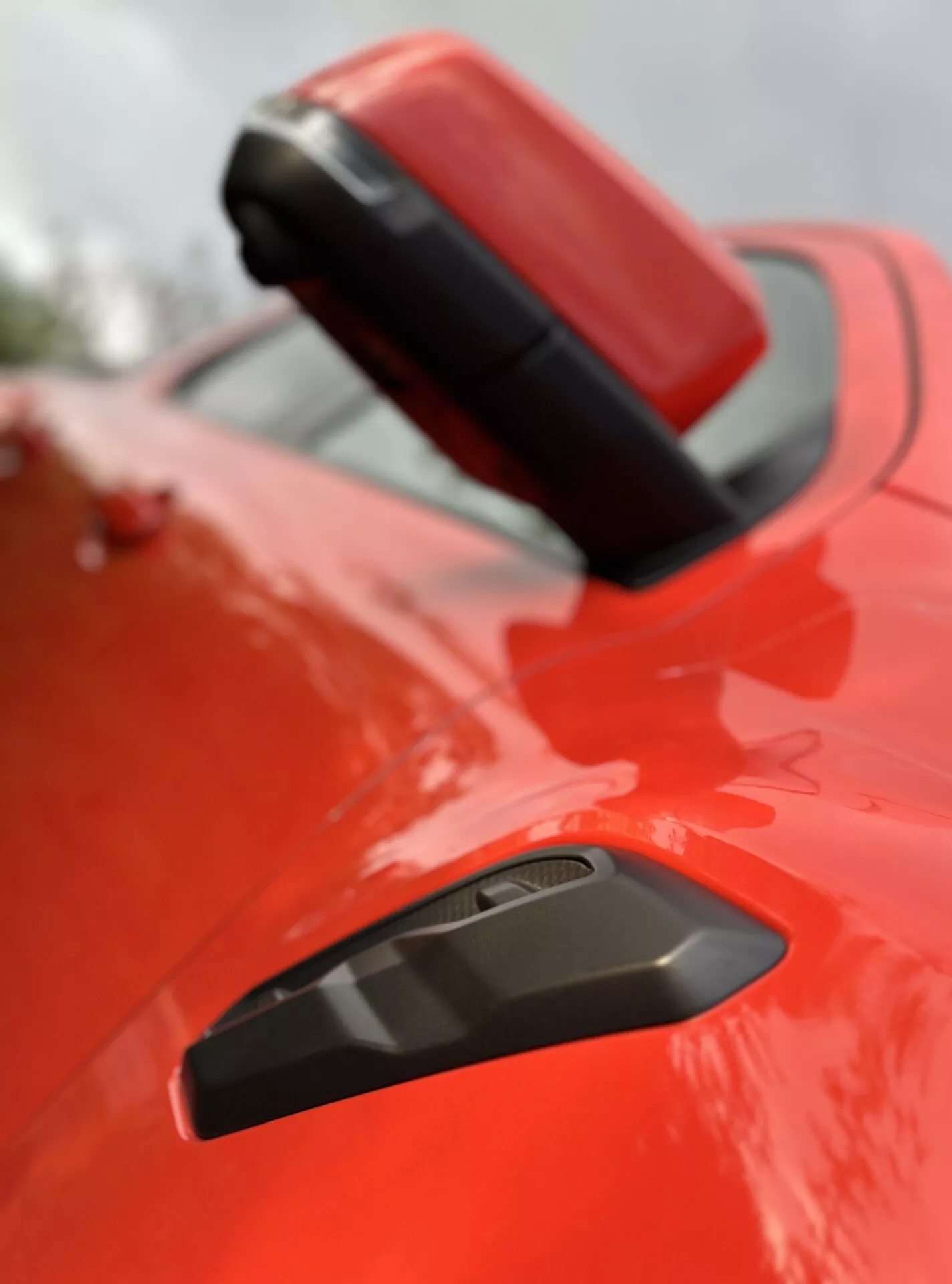 Detailní pohled na zadní blatník a spoiler Fordu Ranger 2022 v lesklé červené barvě s černou mřížkou pro lepší aerodynamiku, zdůrazňující sportovní design pod mělkou hloubkou ostrosti