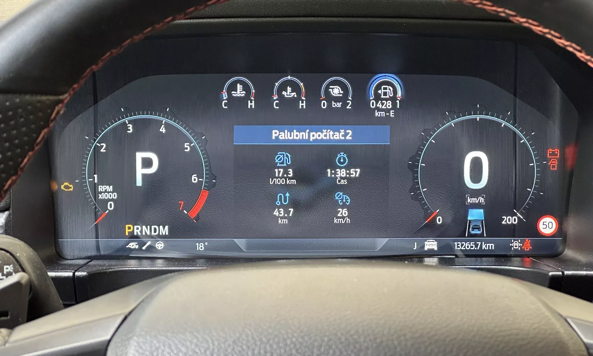 Pohled z místa řidiče na digitální přístrojovou desku Ford Ranger 2022 zobrazující otáčkoměr, ukazatel paliva, rychloměr, teplotní displej a výběr převodovky na moderním palubním panelu vozidla