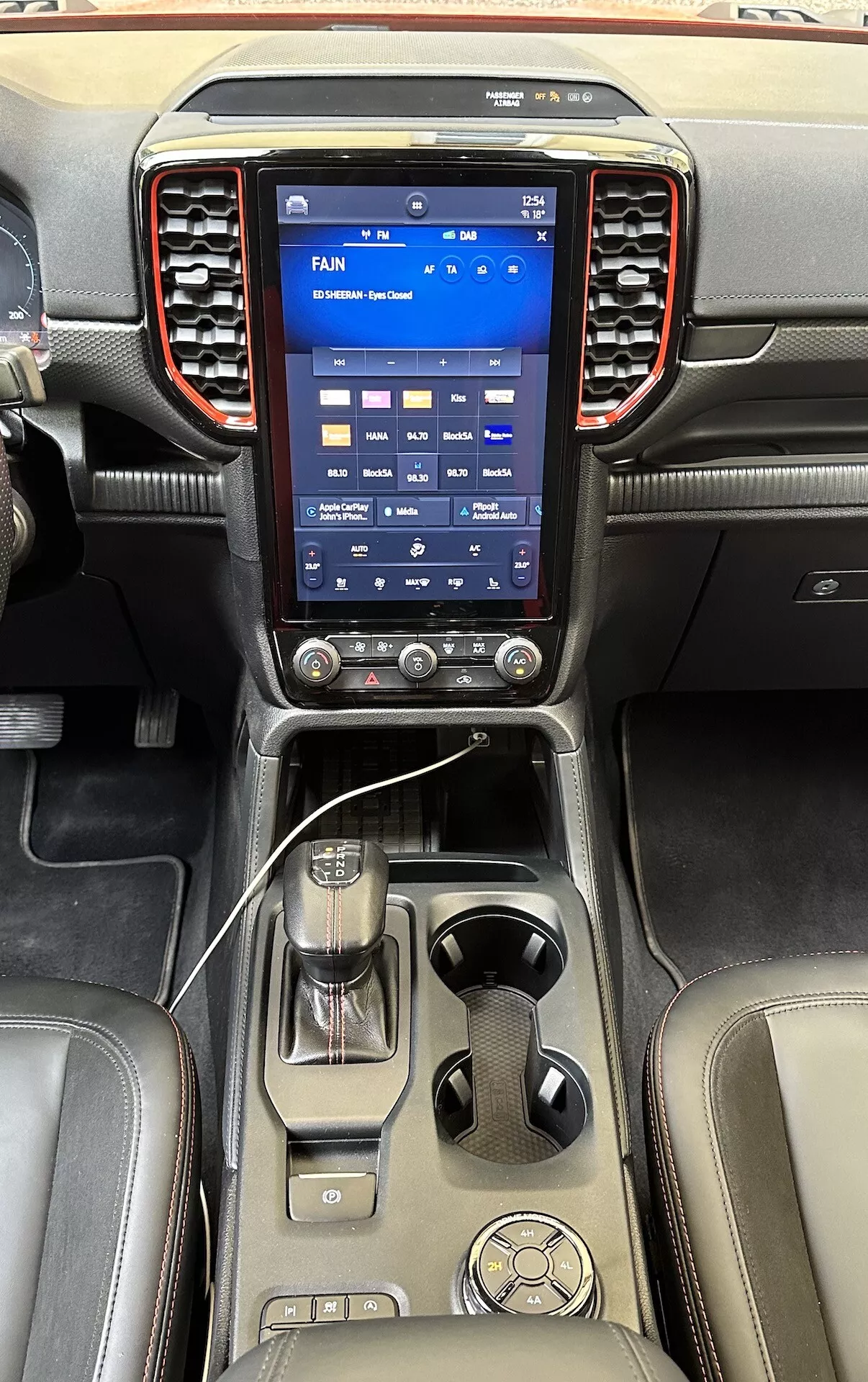 Sofistikovaná středová konzole Ford Ranger 2022 s velkým vertikálním dotykovým informačním systémem, ovladači klimatizace, pákou automatické převodovky a luxusními koženými povrchy