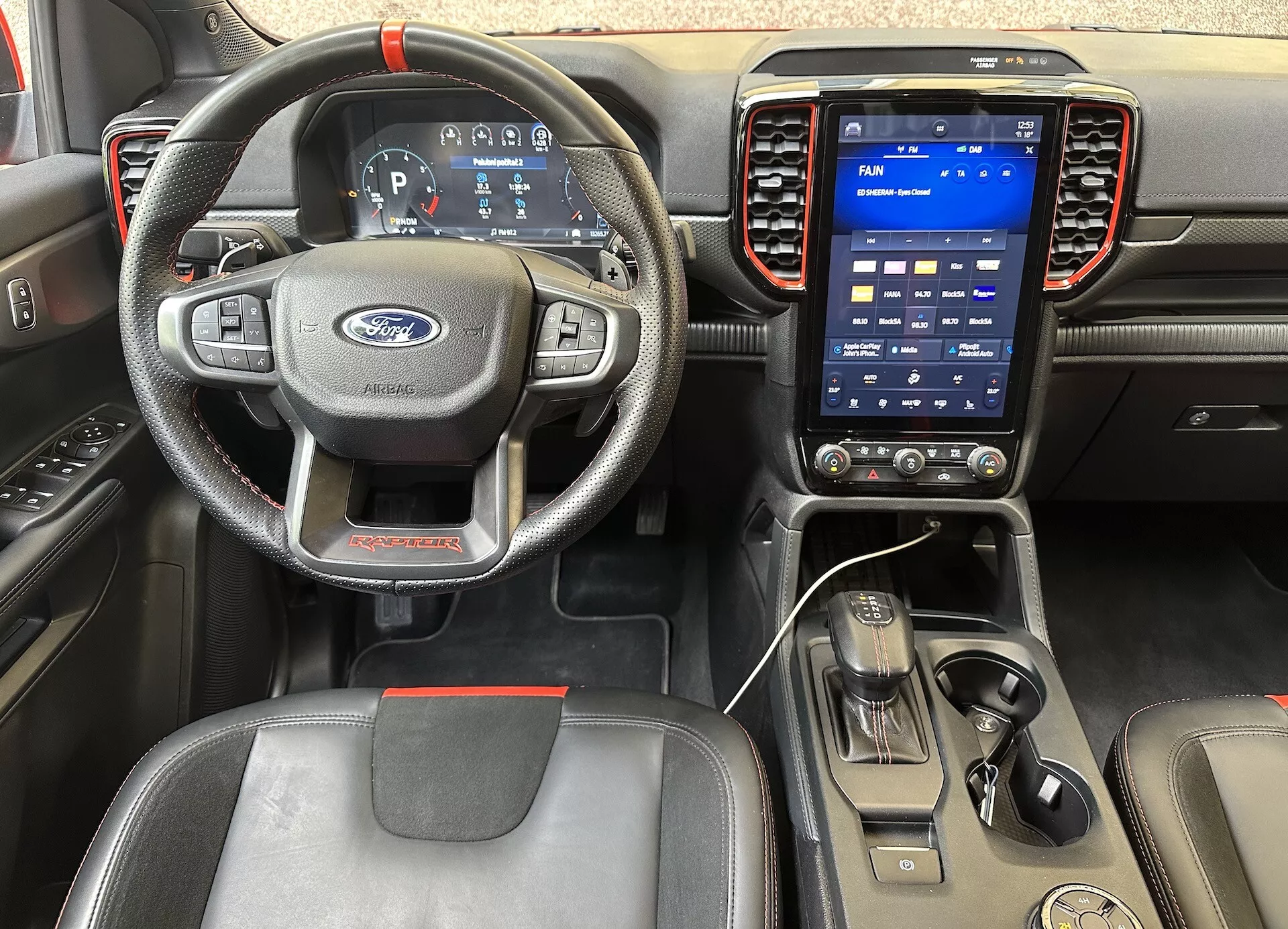 Interiér Ford Ranger 2022 z pohledu řidiče, obsahující volant se třemi rameny s ovladači, digitální přístrojový panel a svisle orientovaný dotykový informačně-zábavní systém na palubní desce