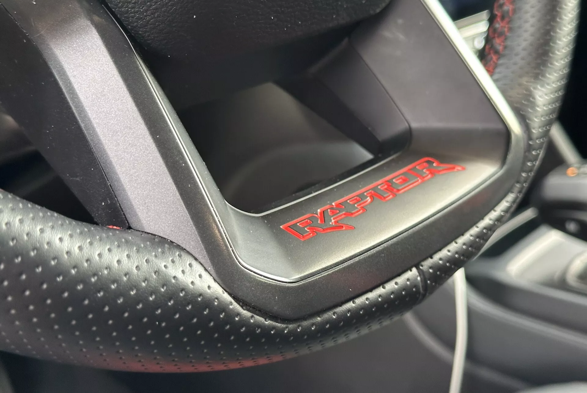 Detailní pohled na volant Dodge Viper ukazuje perforovanou kůži s červeným prošíváním a odznakem 'Viper', což naznačuje sportovně luxusní interiér auta.