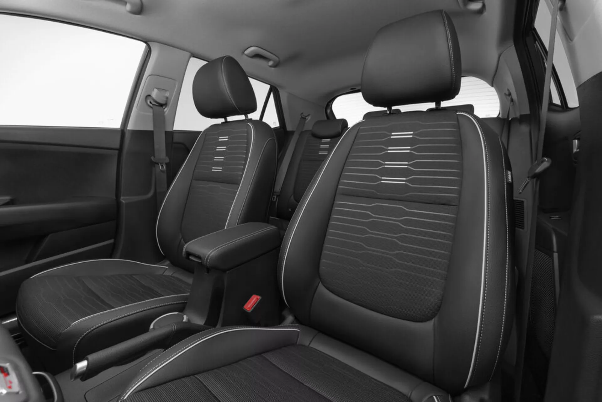 Vysoký úhel pohledu na přední interiér Kia Stonic 2017 s černými sedadly z kůže a detailním prošíváním, středovou konzolou a červenými bodci bezpečnostních pásů s důrazem na design a rozvržení