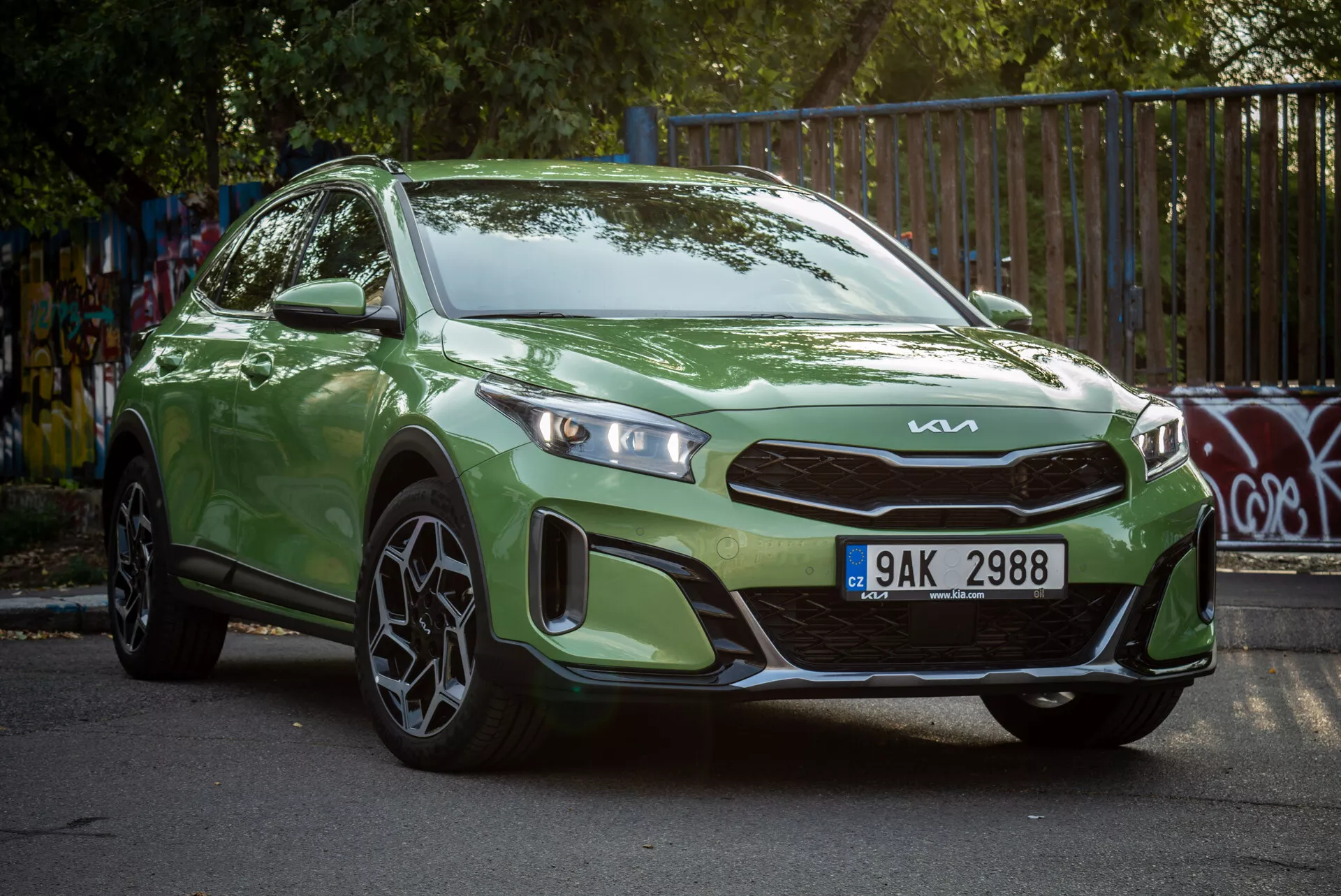 Zelený Kia Xceed 2022 zaparkovaný pod úhlem, předvádějící tříčtvrteční přední pohled s LED světlomety a sportovními slitinovými koly v městském prostředí