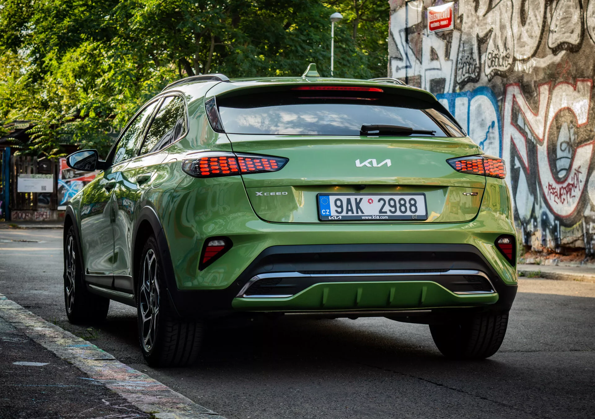 Zadní pohled na zelený crossover/SUV Kia XCeed 2022 ukazující značení, design LED zadních svítilen, umístění registrační značky, estetiku spodního nárazníku a lesklý povrch na městské ulici.