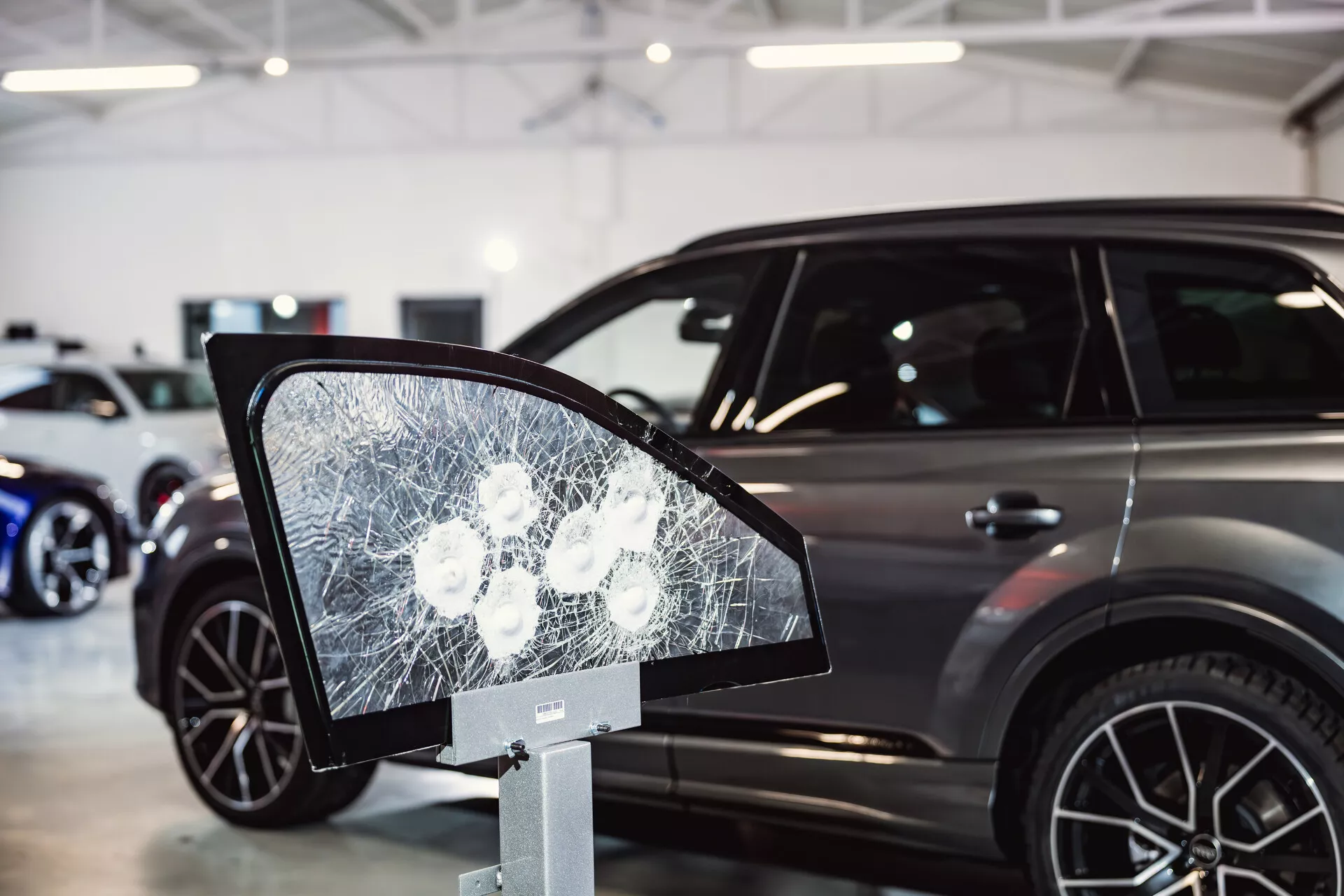 Peugeot 308 model 2022 vystavený v showroomu se zaměřením na rozbitý skleněný displej připomínající boční zrcátko v popředí, naznačující bezpečnostní prvky nebo testy odolnosti a zobrazující elegantní boční profil auta s moderními charakteristikami SUV na pozadí