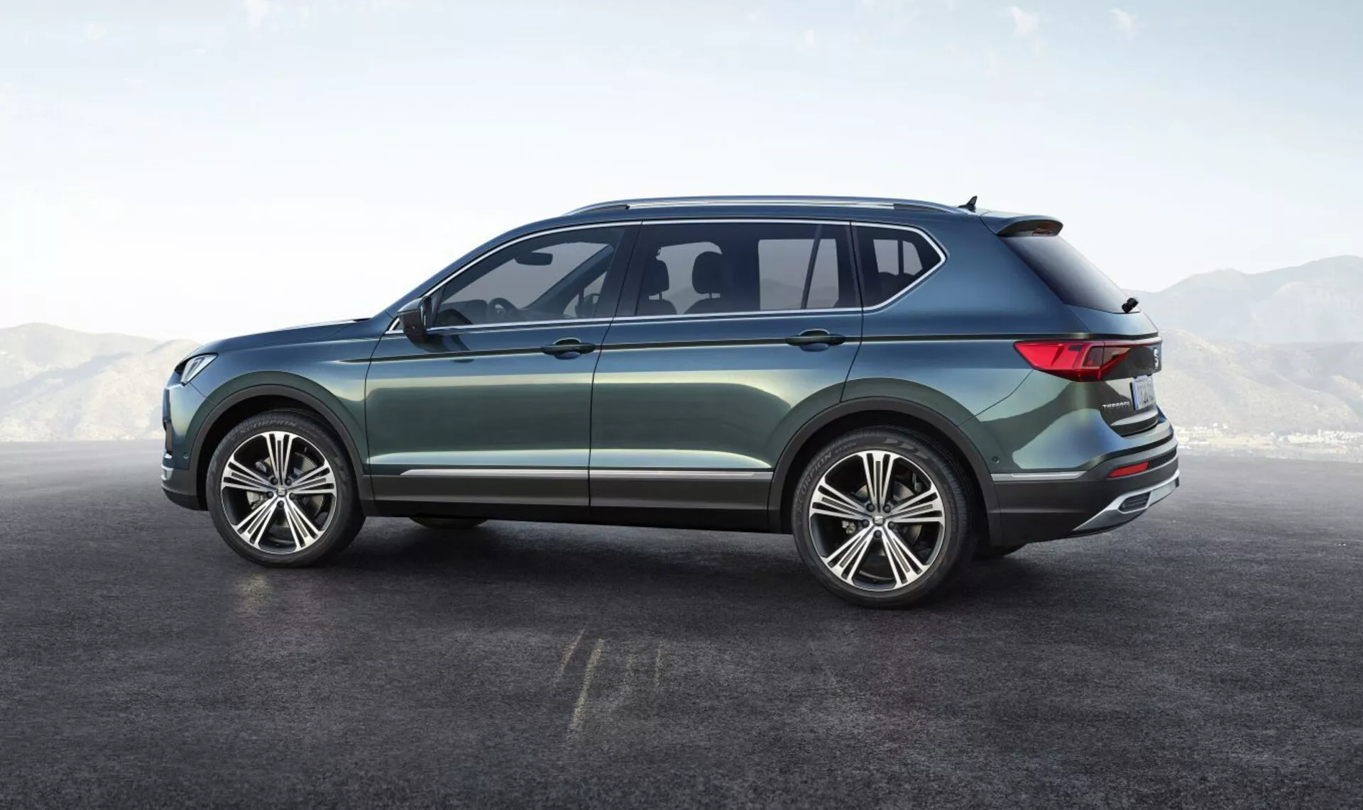 SUV Seat Tarraco 2019 ukazuje svůj boční zadní úhel, představuje velká vícepaprsková slitinová kola, design se čtyřmi dveřmi, elegantní boční okna s malým aerodynamickým zadním oknem, jemně se svažující střechu se zabudovaným spoilerem, obklopující LED zadní světla, metalický lak s chromovanými vnějšími lištami, které zdůrazňují jeho moderní a všestranný design