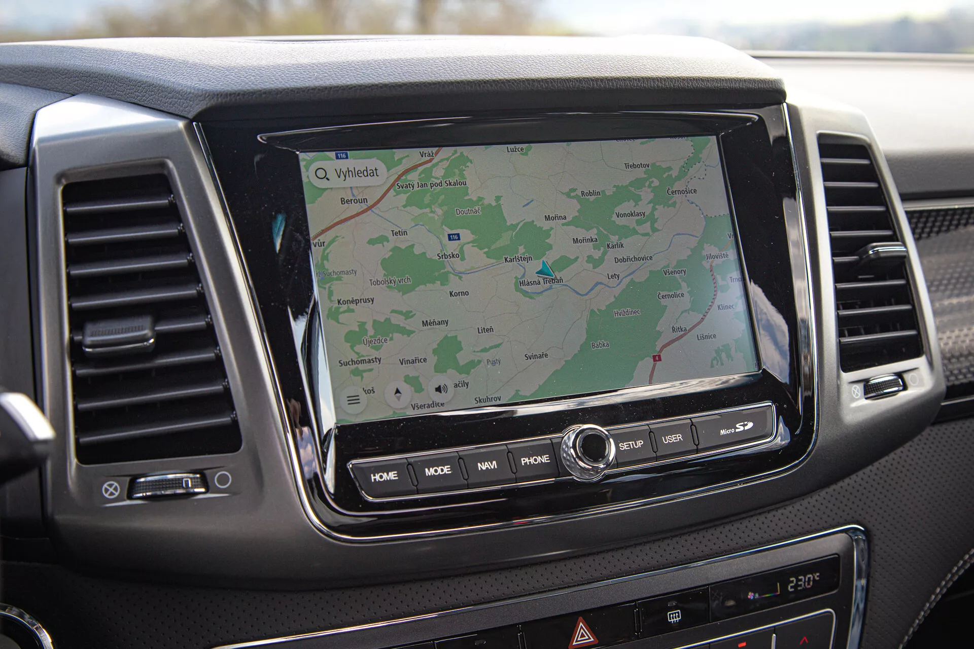 Přístrojová deska SsangYong Musso 2022 ukazující dotykový informační systém s GPS navigací, vzduchové ventily a ovládací tlačítka, pohled z perspektivy spolujezdce.