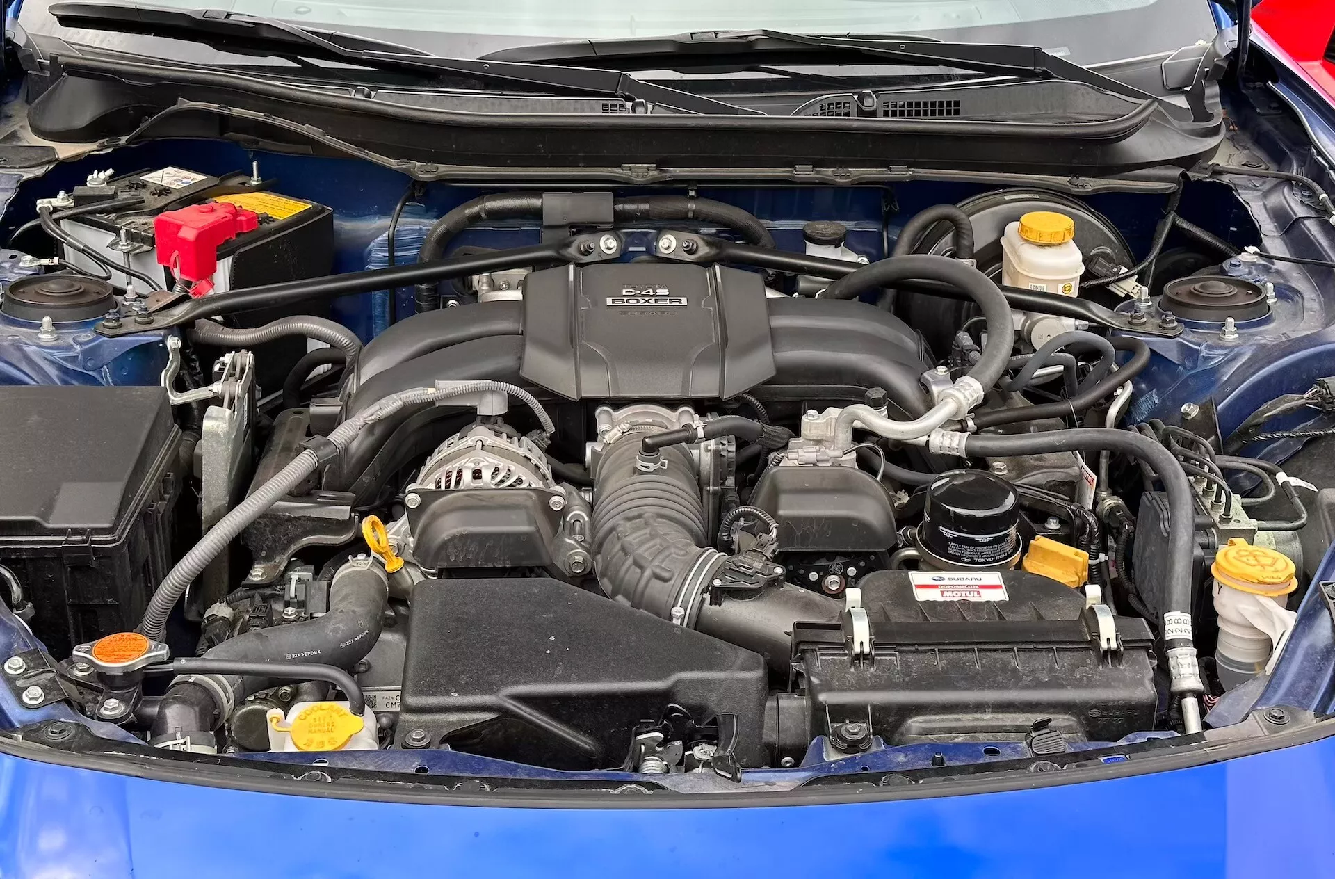 Detailní pohled na motorový prostor Subaru BRZ 2023 s viditelným motorem BOXER, baterií, zásobníky kapalin a sáním vzduchu
