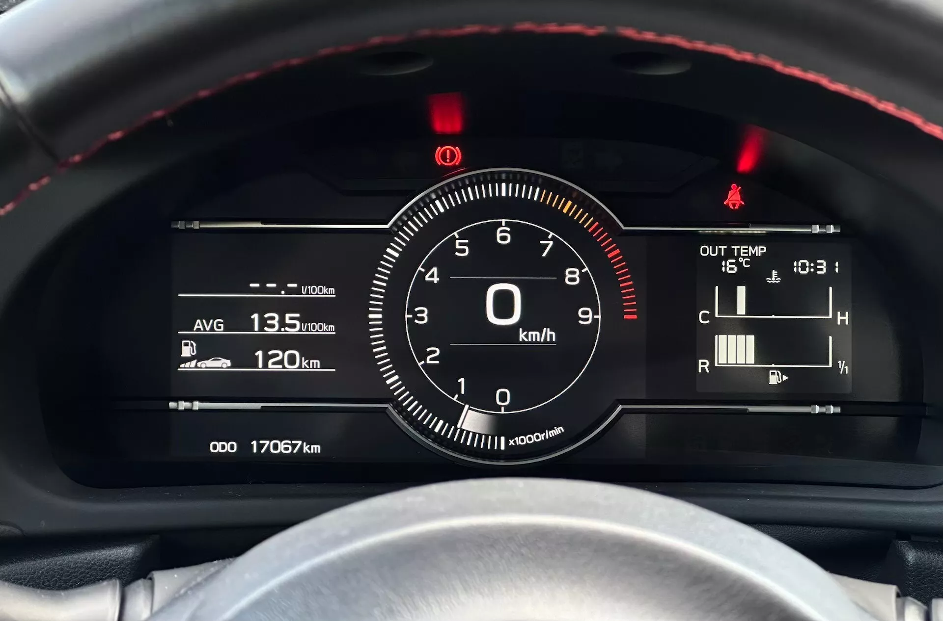 Detailní pohled na přístrojovou desku Subaru BRZ 2023 se zaměřením na rychloměr a další ukazatele z pohledu řidiče, s červeně prošitým volantem, kombinací digitálních a analogových ukazatelů a technologických indikátorů jako jsou účinnost paliva, teplota a údaje o tachometru.