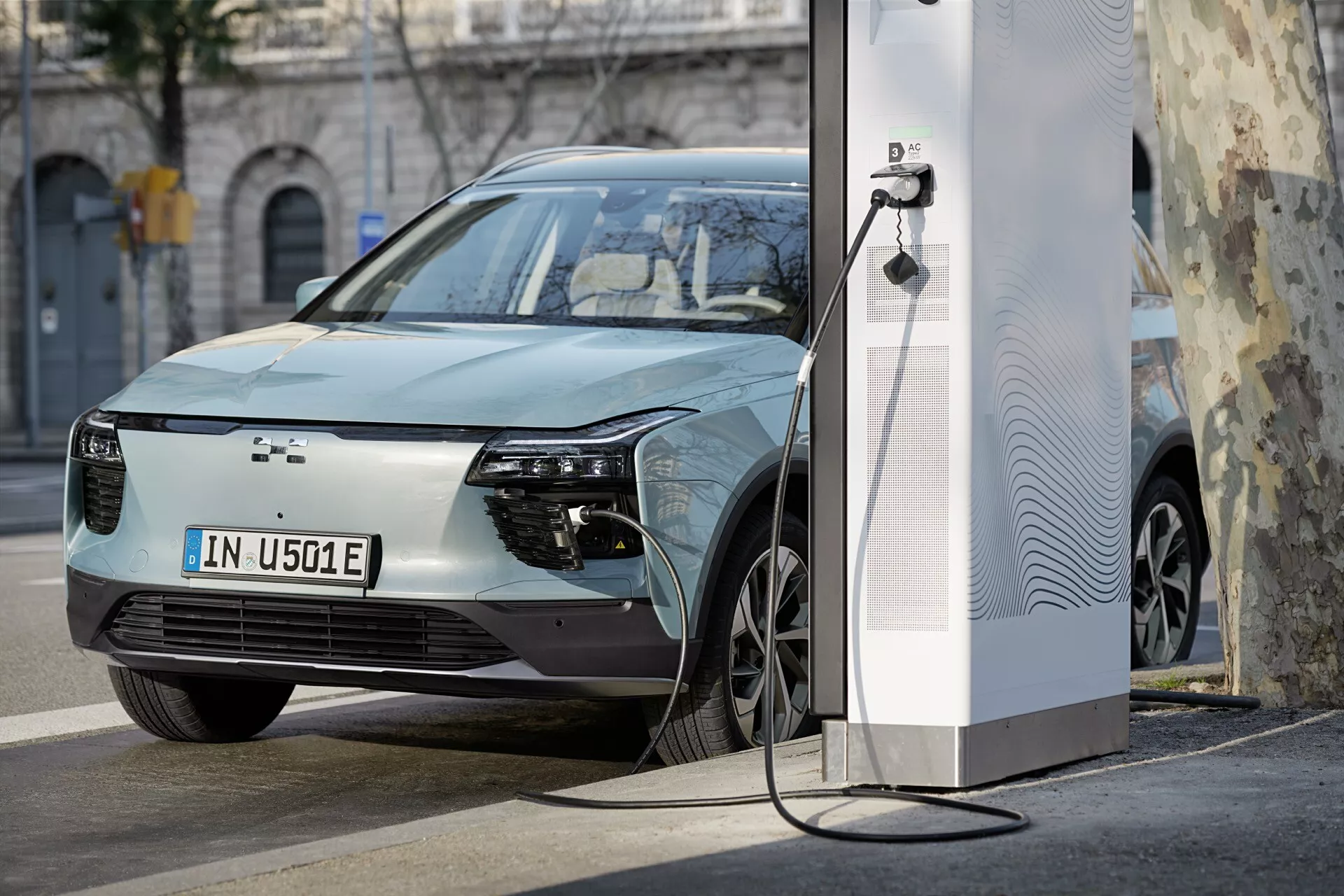 Aiways U5 1. generace z roku 2020 se nabíjí na elektrické stanici, předvádí elegantní design včetně minimalistické mřížky a moderních slitinových kol, v městském prostředí