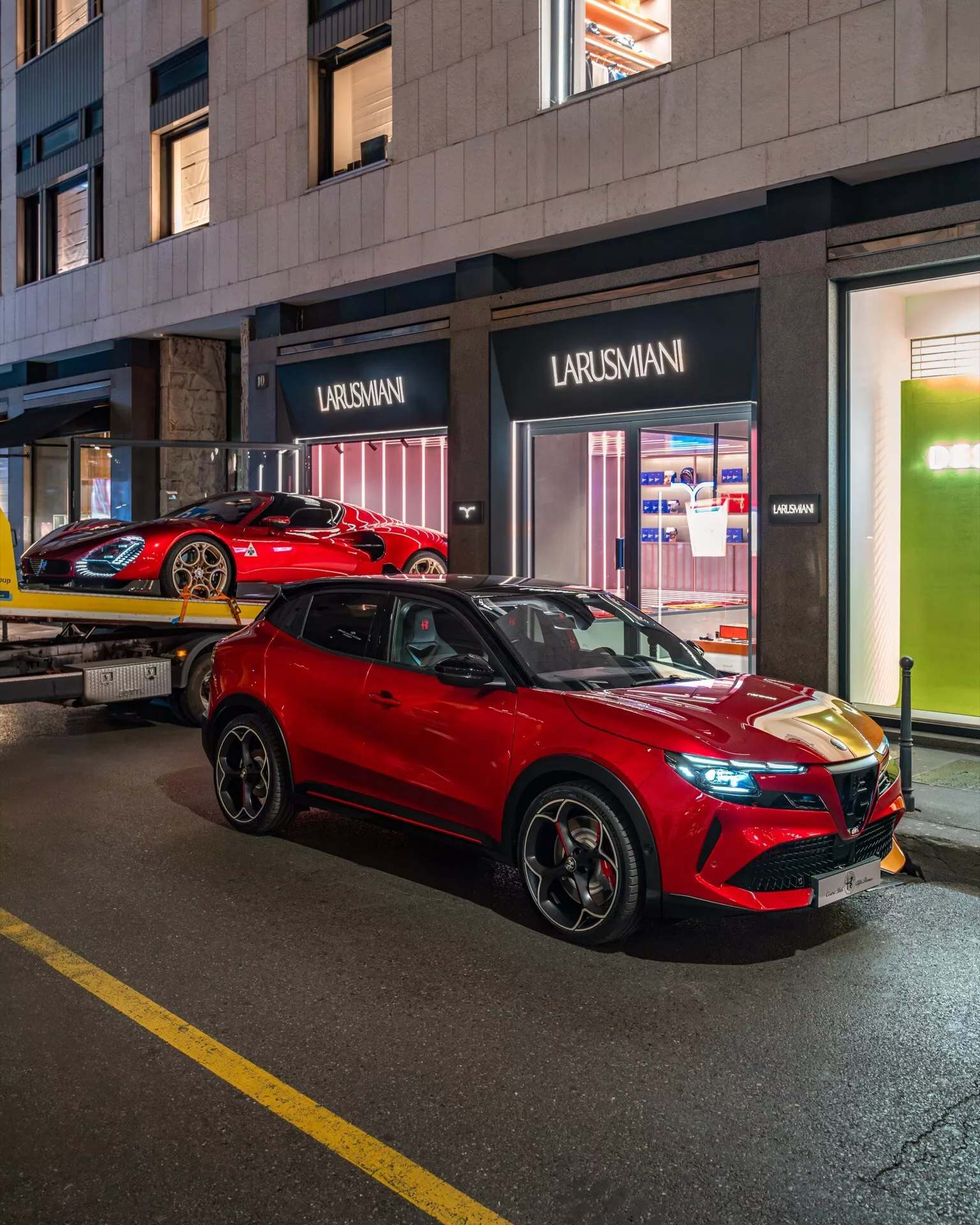 Alfa Romeo Junior 2024 výrazné červené SUV zaparkované na osvětlené městské ulici v noci, předvádí elegantní design, LED světlomety a slitinová kola z pohledu ze tří čtvrtin zepředu