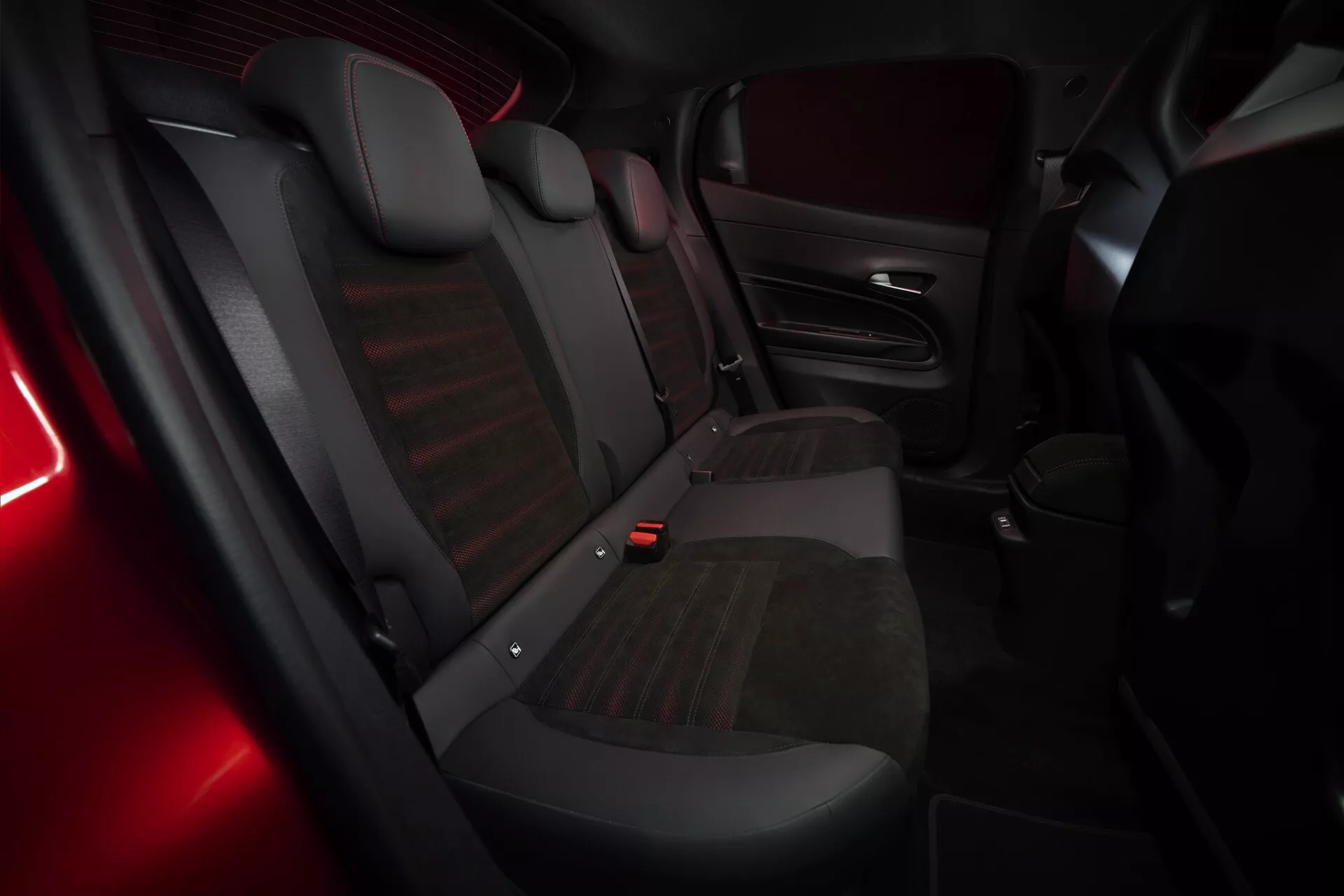 Vnitřní pohled na Alfa Romeo Junior (966) pro rok 2024 s důrazem na zadní cestovní část s lavicí pro tři osoby, kombinovaným čalouněním a jemným červeným ambientním osvětlením
