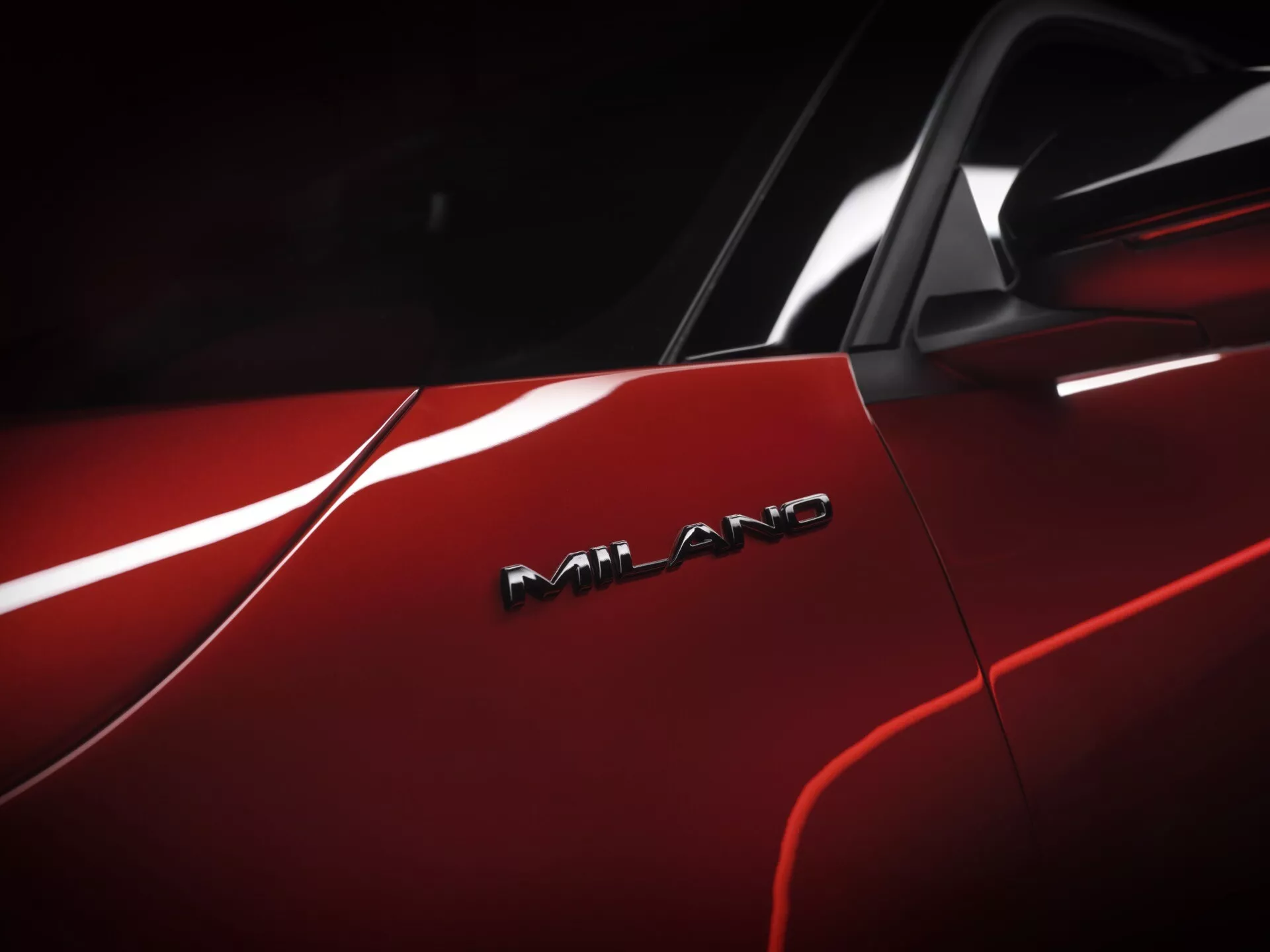 Detailní pohled na červený Alfa-Romeo Junior 2024 s lesklým povrchem a odznakem AMG, což naznačuje jeho vysokou výkonnost a nadřazený design