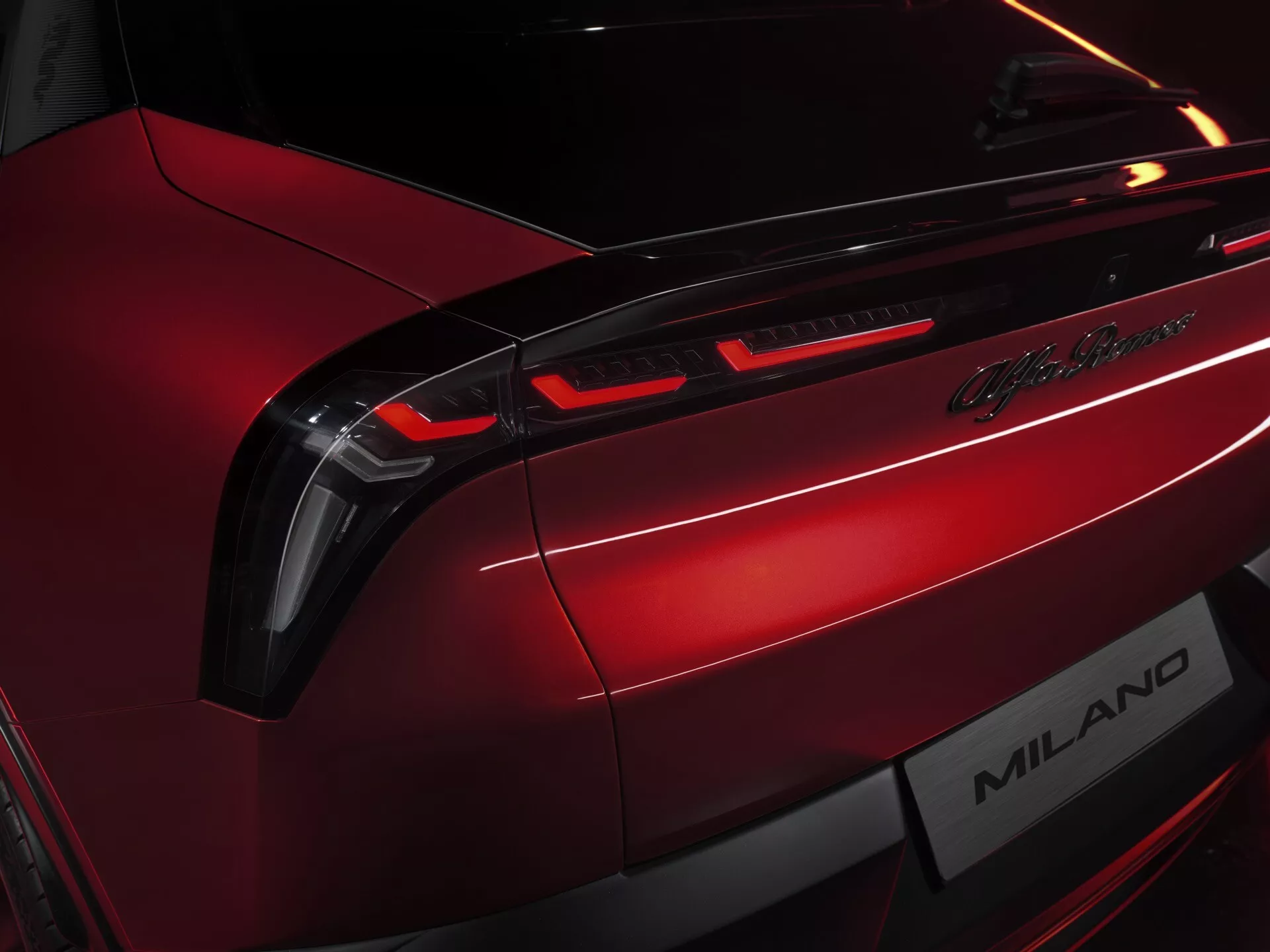 Detailní pohled na zadní část vozu Alfa Romeo Junior 2024, zobrazující LED zadní světla, odznak Lamborghini Milano, v metalické červené