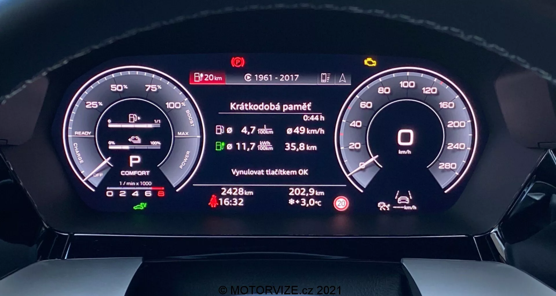 Detailní pohled na digitální přístrojový cluster Audi A3 2020 Sportbacku z pohledu řidiče. Přímá perspektiva zobrazuje detailní digitální displeje otáčkoměru, indikátoru baterie, volby převodovky, jízdního režimu, průměrné rychlosti, spotřeby paliva, vzdálenosti do vyprázdnění nádrže, vnější teploty a stavové zprávy o nedávné údržbě. Moderní design integruje digitální a analogové prvky pro vyvážený high-tech a intuitivní zážitek.