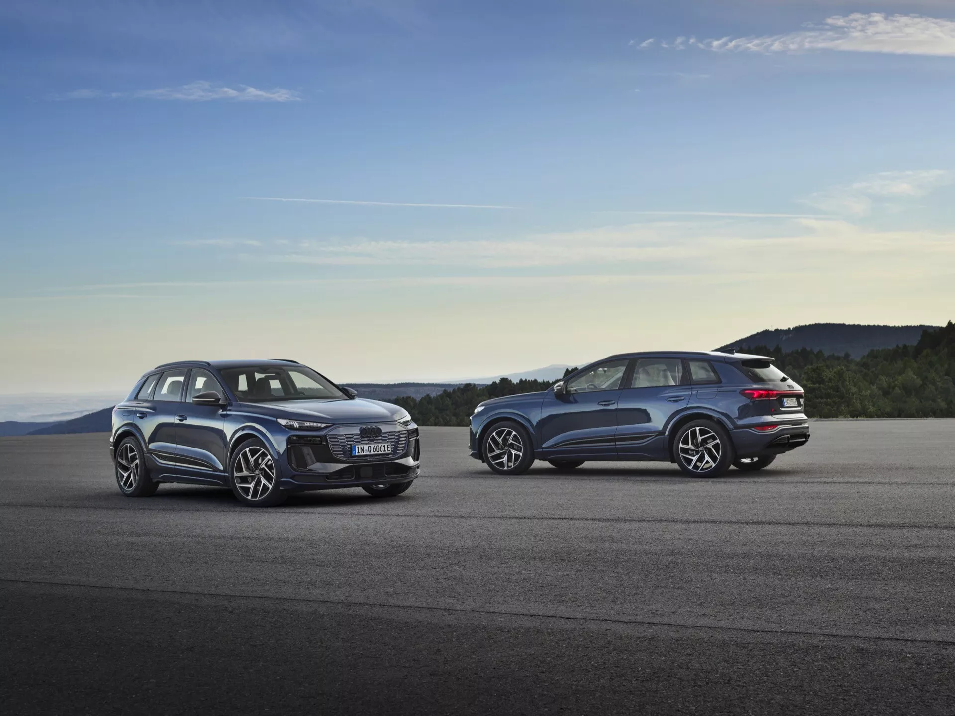 Audi Q6 e-tron 2024 (GF) zaparkovaný při západu slunce, který ukazuje jeho elegantní aerodynamický design, futuristické LED světlomety, prostorný interiér, velká litá kola a pokročilý elektrický pohon.