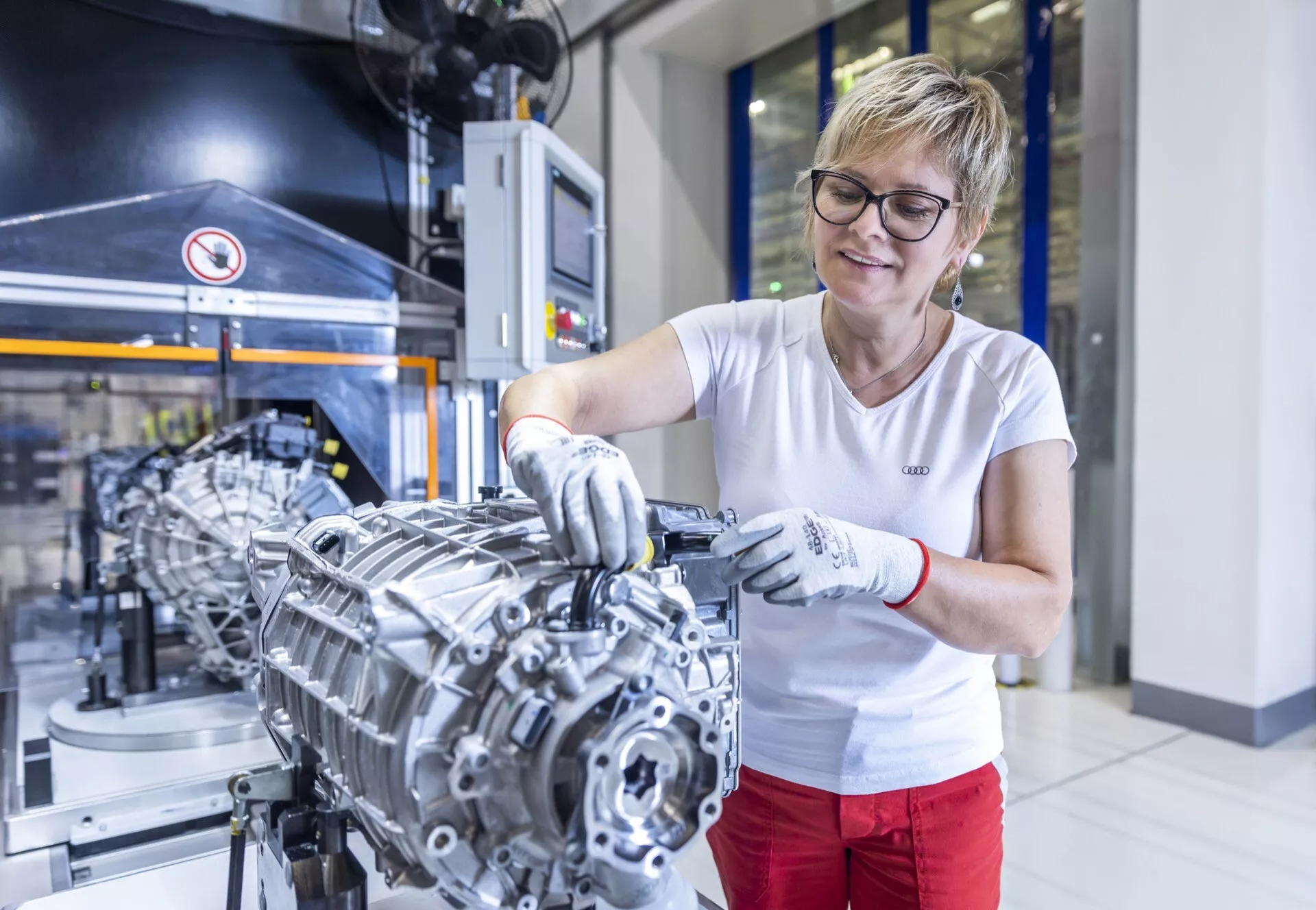 Profesionální technička se soustředí na montáž převodovky vozidla ve vyspělém továrním prostředí