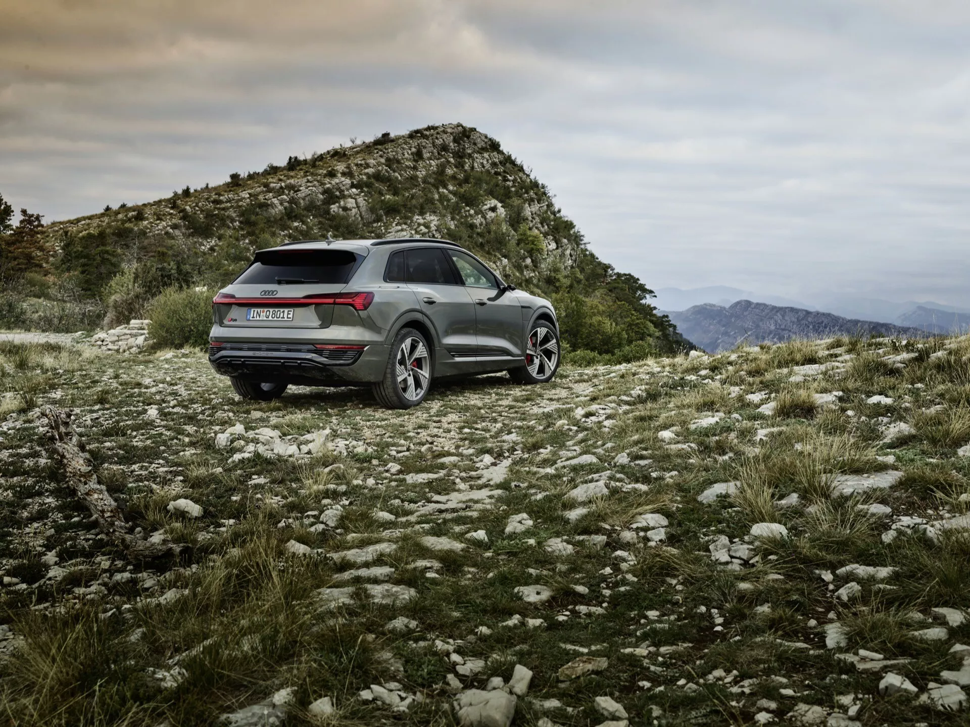 Audi Q8 e-tron 2023 s metalickým povrchem, umístěný v drsném venkovním terénu, ukazuje schopnosti pro jízdu v terénu, sportovně-praktický design s LED zadními světly, slitinovými koly a pokročilými technologickými funkcemi