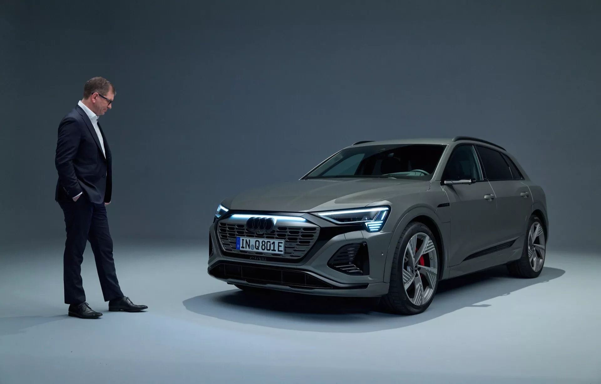 Audi Q8 e-tron 2023 v ateliérovém nastavení, prezentující moderní elektrický luxusní vůz se štíhlým designem, pohled z nízkého úhlu tříčtvrteční přední perspektivy na pozadí s přechodem, s plně LED světlomety a velkými slitinovými koly