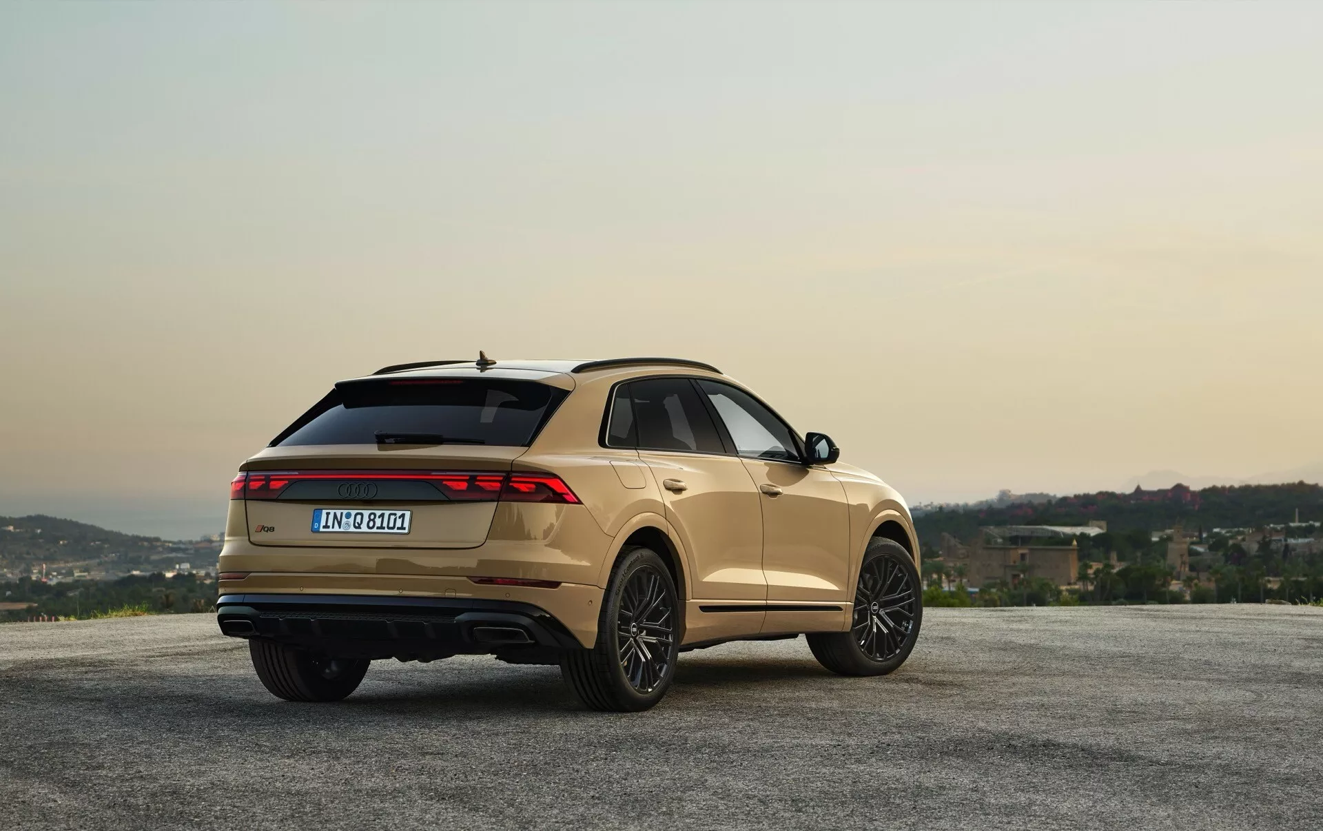 Audi Q8 2023 (4M-Facelift) v metalickém provedení zaparkované v panoramatickém výhledu s kopců a oblohou na úsvitu/západu slunce, zobrazení z úhlu tří čtvrtin zadní části pro náhled na design a funkce