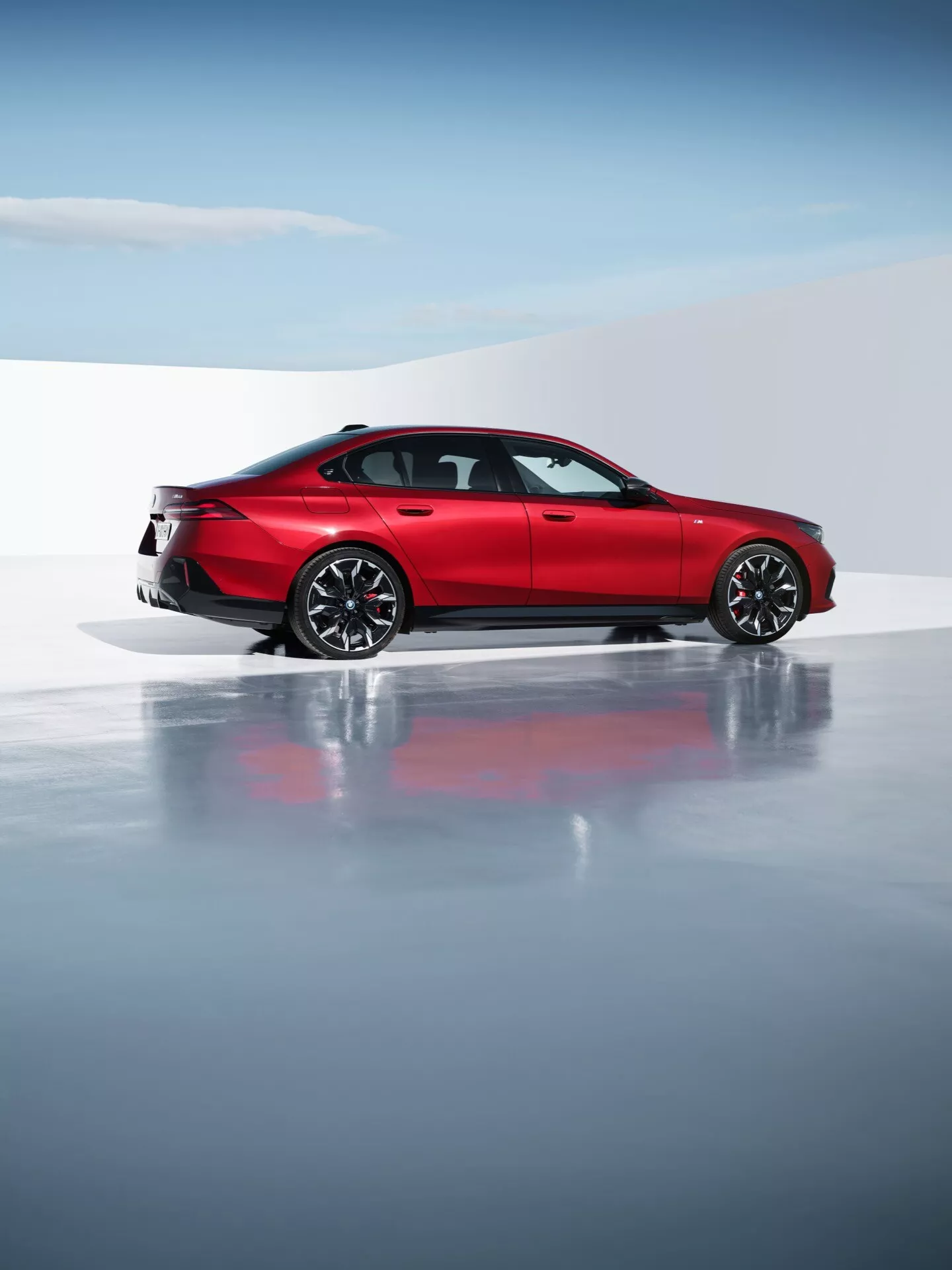 BMW řady 5 (G60-G61) 2023 ve výrazné červené barvě představující jeho aerodynamický design a sportovní eleganci, s vícepaprskovými slitinovými koly, moderními LED zadními světly a dvojitým výfukovým systémem v profesionálním studiovém nastavení