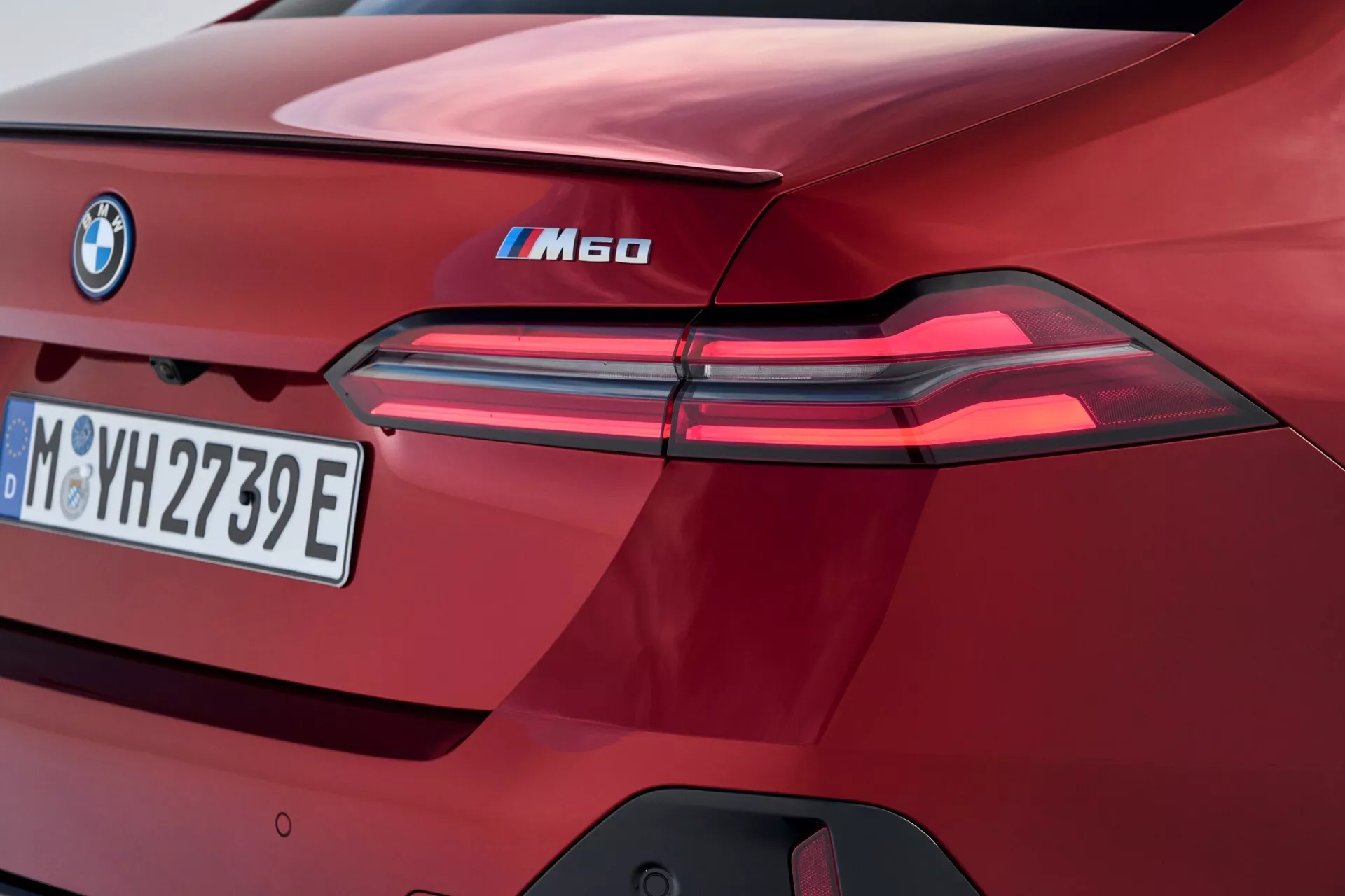 Detailní pohled na zadní část BMW řady 5 iM60 pro rok 2023, zdůrazňující LED zadní světla, označení iPerformance, evropskou poznávací značku, vysoce lesklý vínový lak a výrazné designové prvky