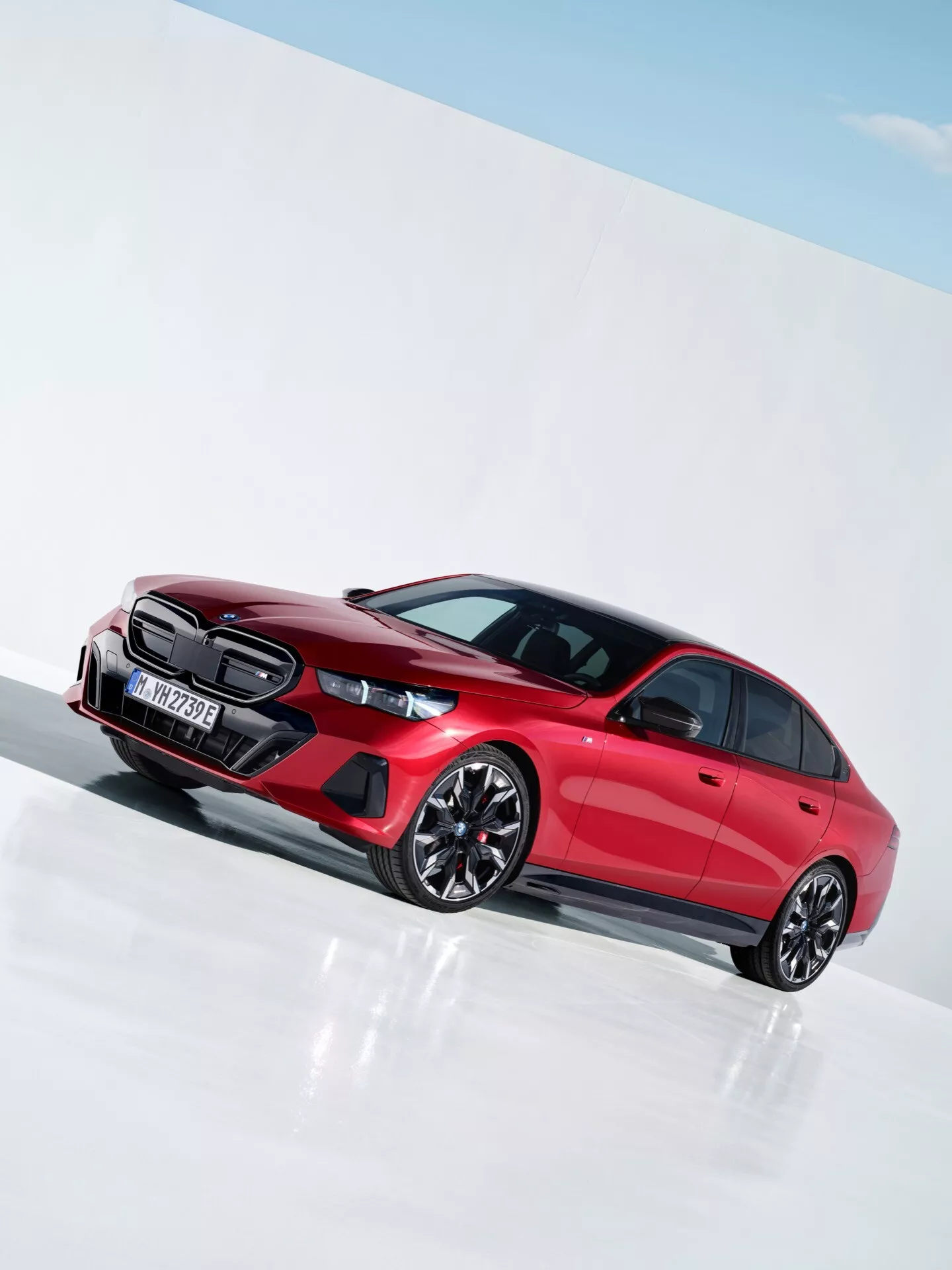 BMW řady 5 z roku 2023 (G60-G61) ve výrazné červené barvě, která zdůrazňuje sportovní design s výraznou mřížkou chladiče, LED světlomety, tvarovanými dveřními panely a vícepatrovými slitinovými koly v jasně osvětleném studiu