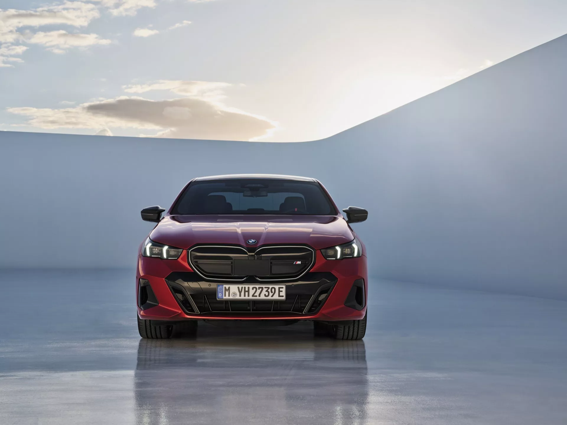 Přední pohled na BMW řady 5 2023 (G60-G61) předvádějící LED světlomety, složitou mřížku a označení EV na lesklé podlaze showroomu pod jemným osvětlením