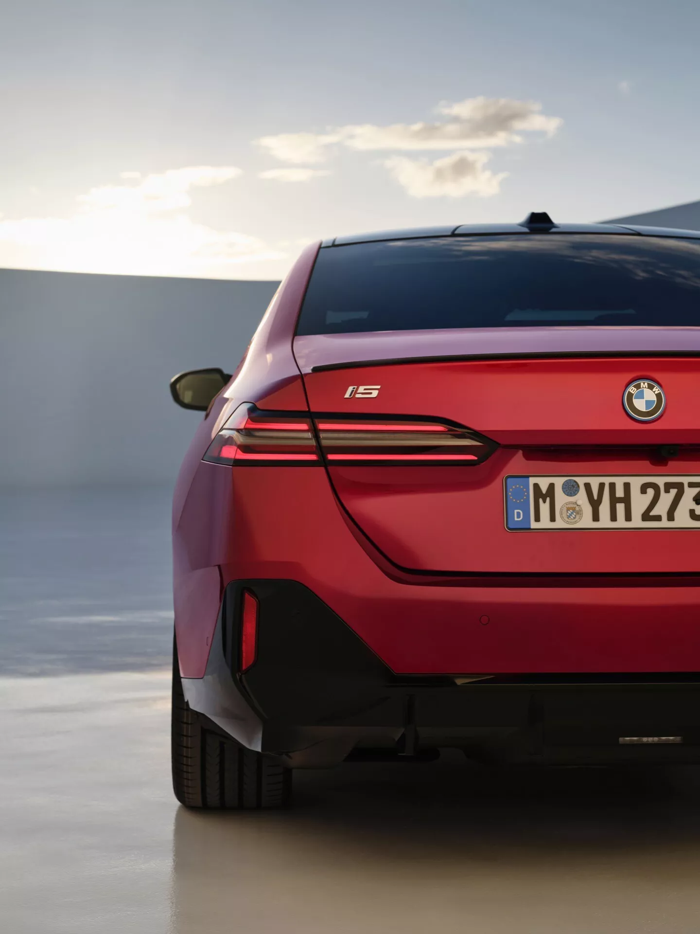 Detailní pohled na zadní část BMW řady 5 2023 (G60-G61) zobrazující LED zadní světla, elegantní design a emblem modelu 'i5' na pozadí sofistikovaného venkovního prostředí