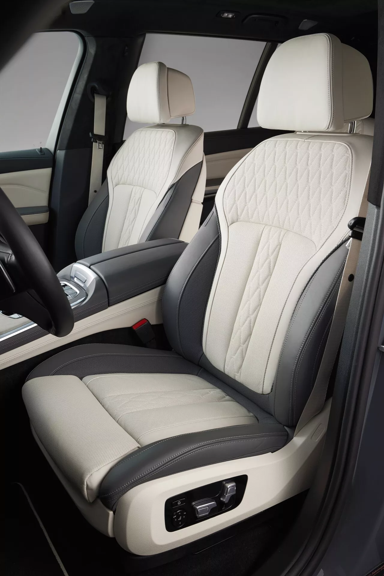 Detailní pohled na interiér BMW X7 2022 (G07-facelift), zaměřený na prémiové sedadlo spolujezdce z kůže ve dvou tónech s prošíváním ve tvaru diamantů, elektronické nastavení, v kombinaci s luxusním designem dveří a středové konzoly