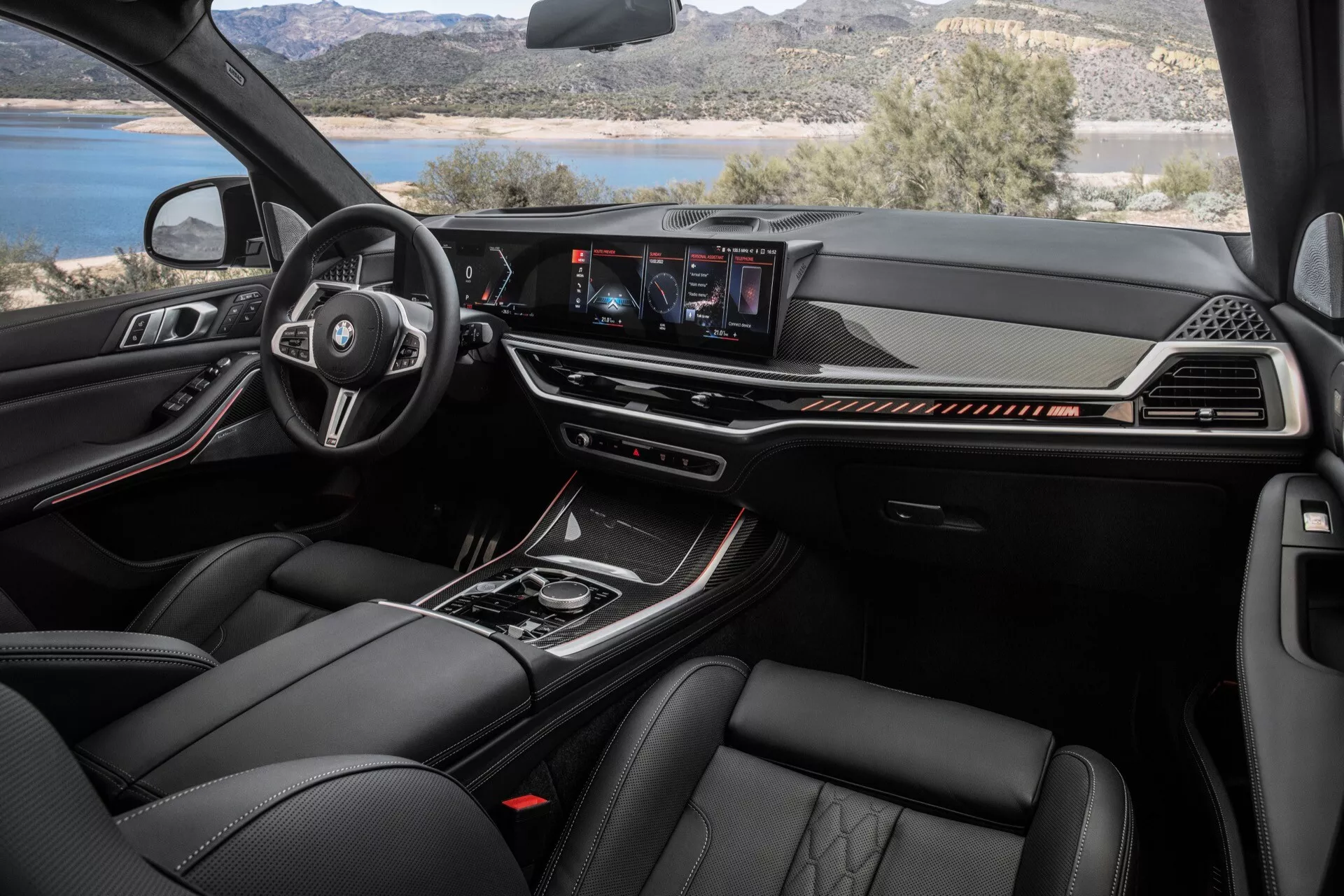 Interiér BMW X7 (G07-facelift) z roku 2022 s vícefunkčním volantem potaženým kůží s logem výrobce, digitálním přístrojovým panelem, centrálním dotykovým infotainment systémem a prémiovými materiály včetně kožených sedadel s pokročilými funkcemi klimatizace z perspektivy předního spolujezdce