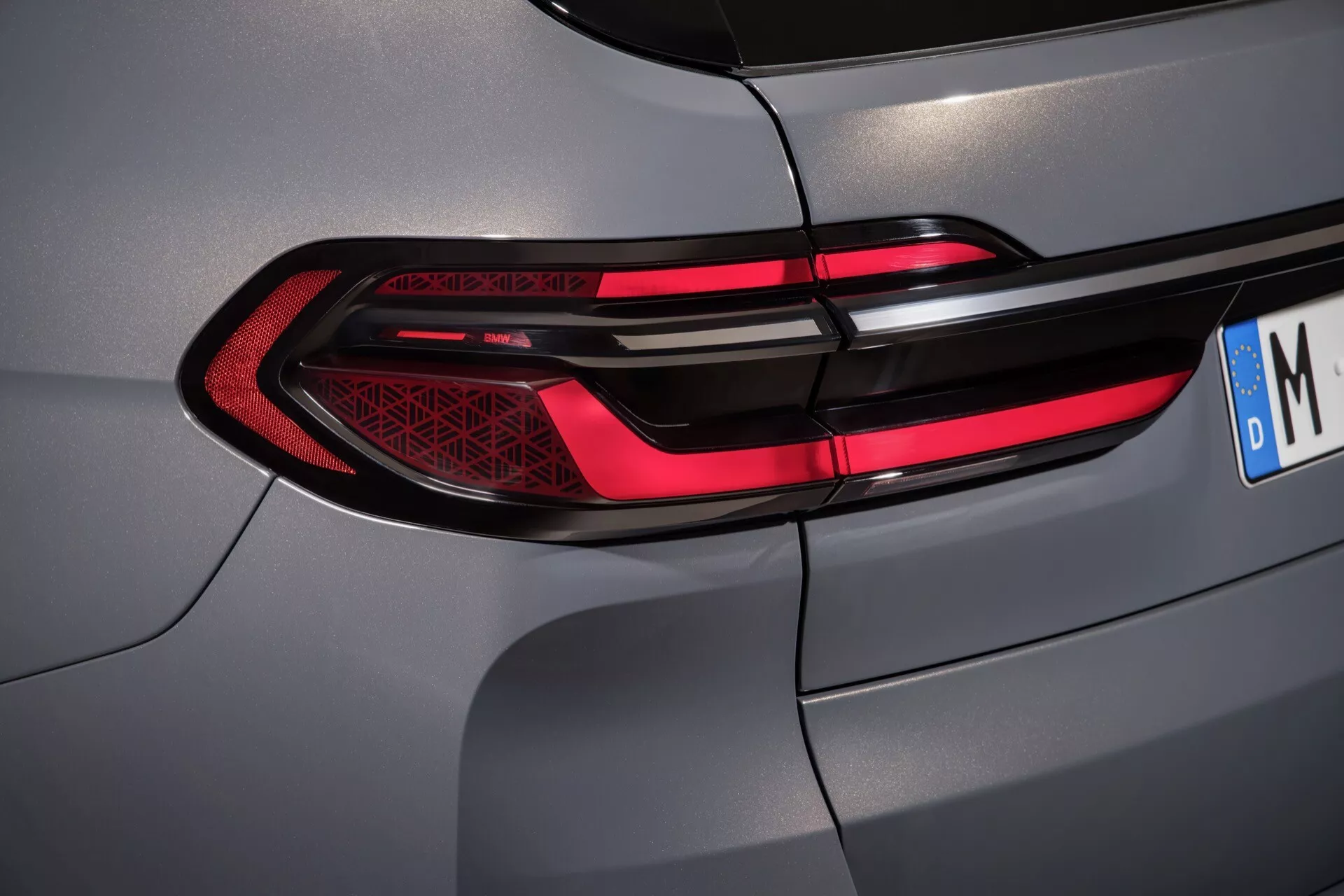 Detailní pohled na zadní světlo BMW X7 2022 (G07 Facelift) se štíhlým LED designem a metalickou šedou barvou, ukazující pokročilou technologii osvětlení a vysokou kvalitu zpracování.