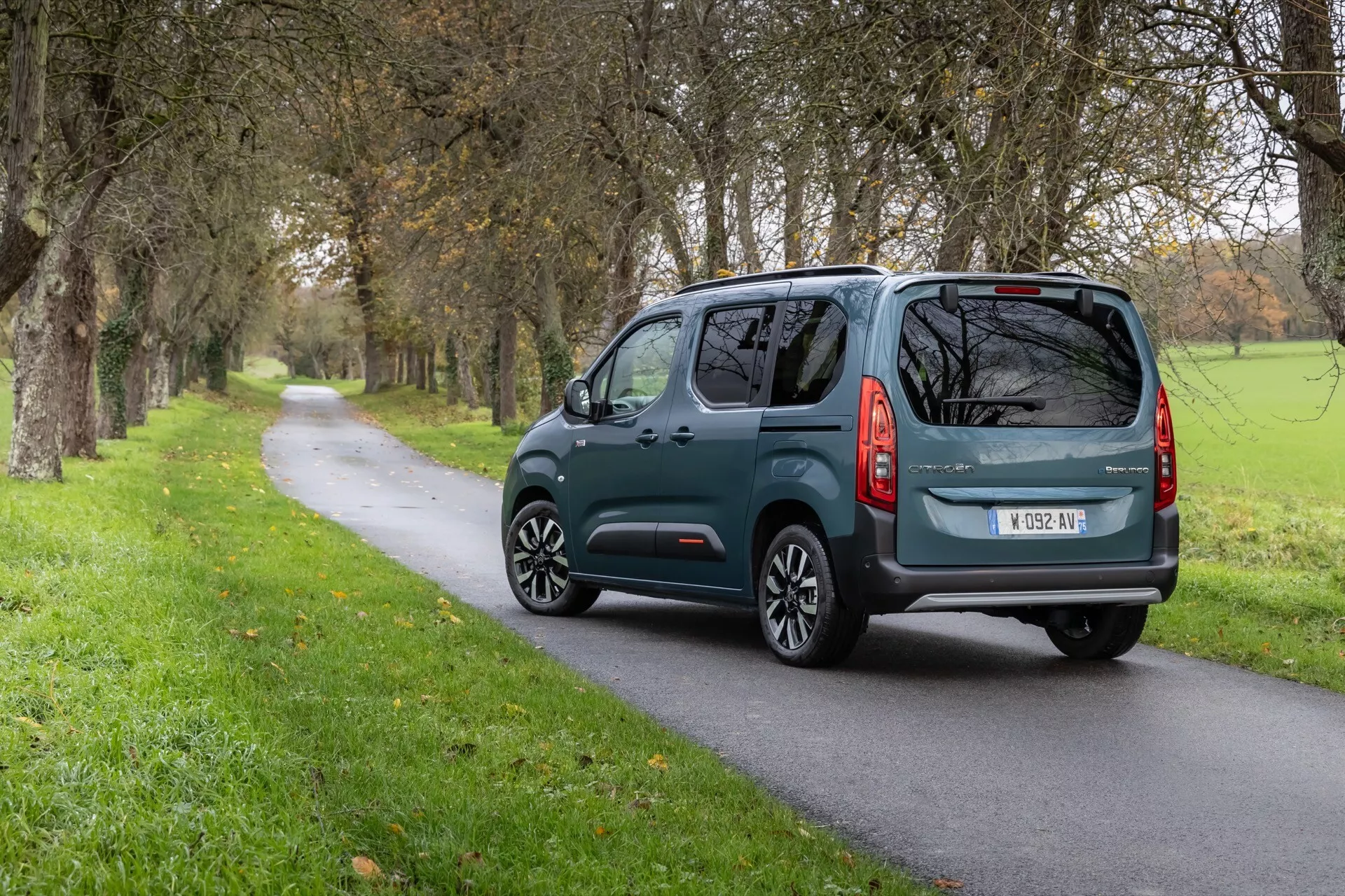 Zadní tříčtvrteční pohled na Citroen Berlingo 3. generace facelift 2024 na venkovské silnici s evropskou registrační značkou, zadním stěračem a moderním designem zadních světel.