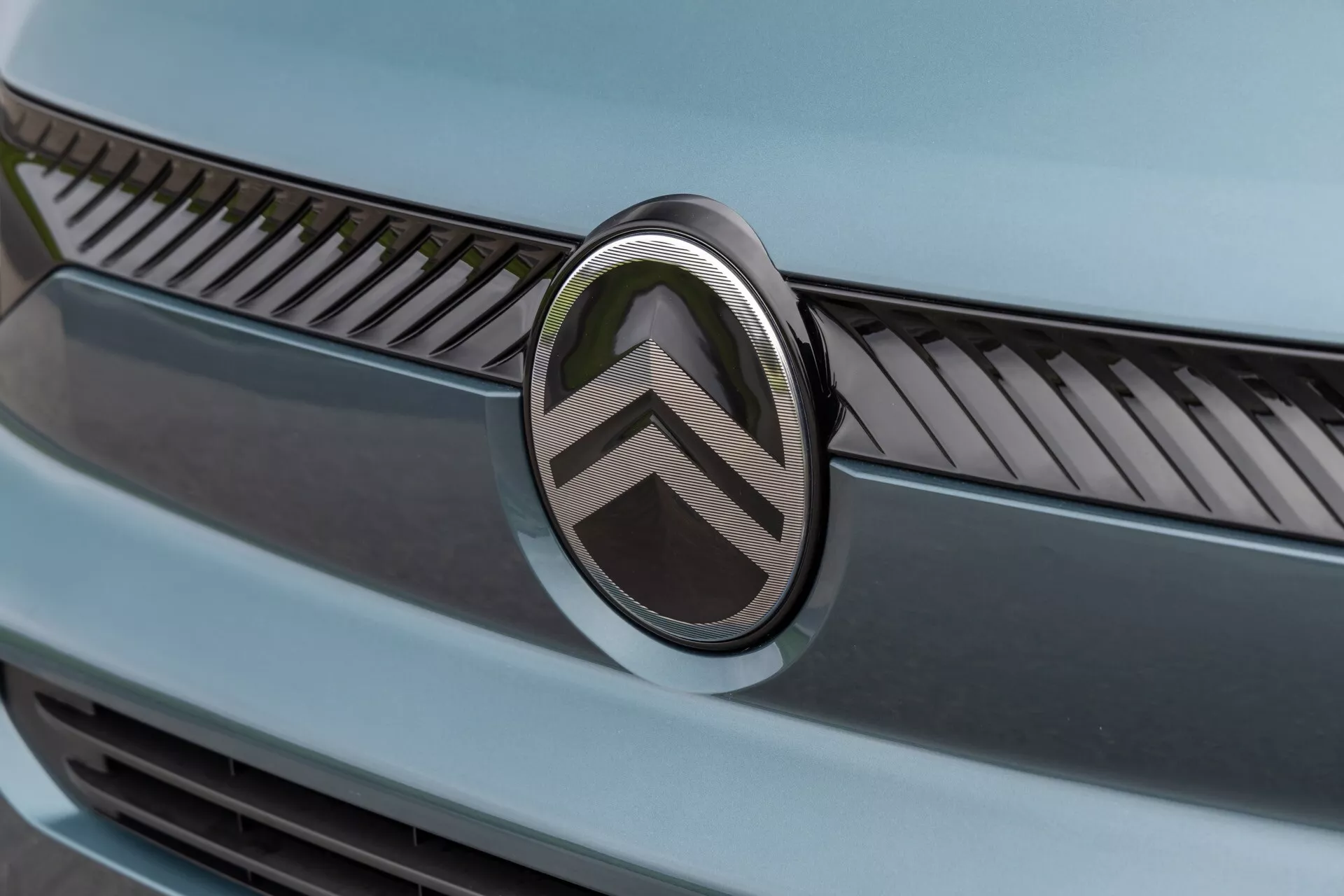 Detailní pohled na přední část Citroënu Berlingo 2024 po faceliftu, zobrazující dvojitý ševronový logo a detailně propracovanou mřížku s kovovými finiši pod měkkým osvětlením