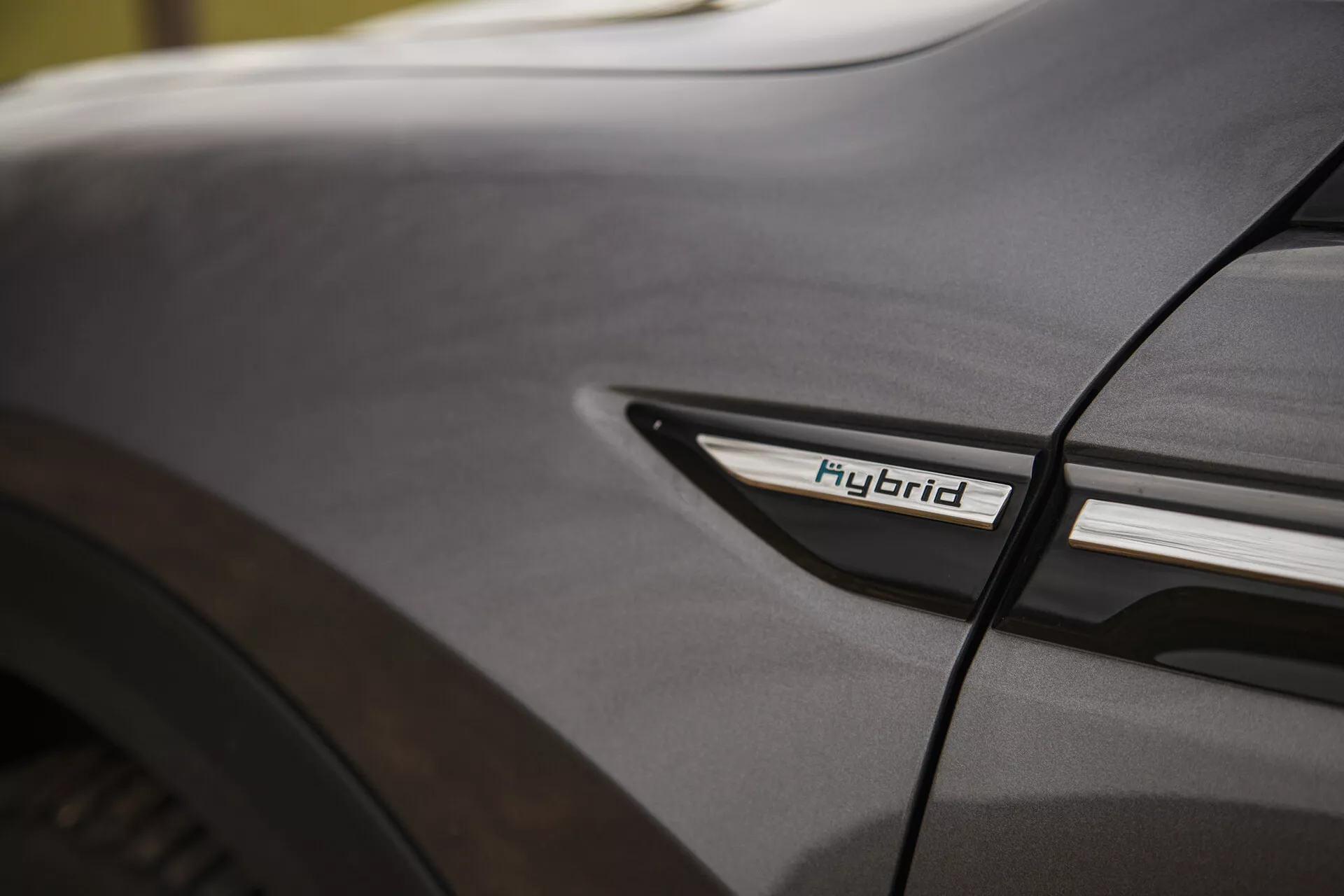 Detailní pohled na Citroen C5-X 2022 s označením Hybrid na nižším bočním profilu u zadního kola, předvádějící hybridní technologii a designovou estetiku v měkkých světelných podmínkách