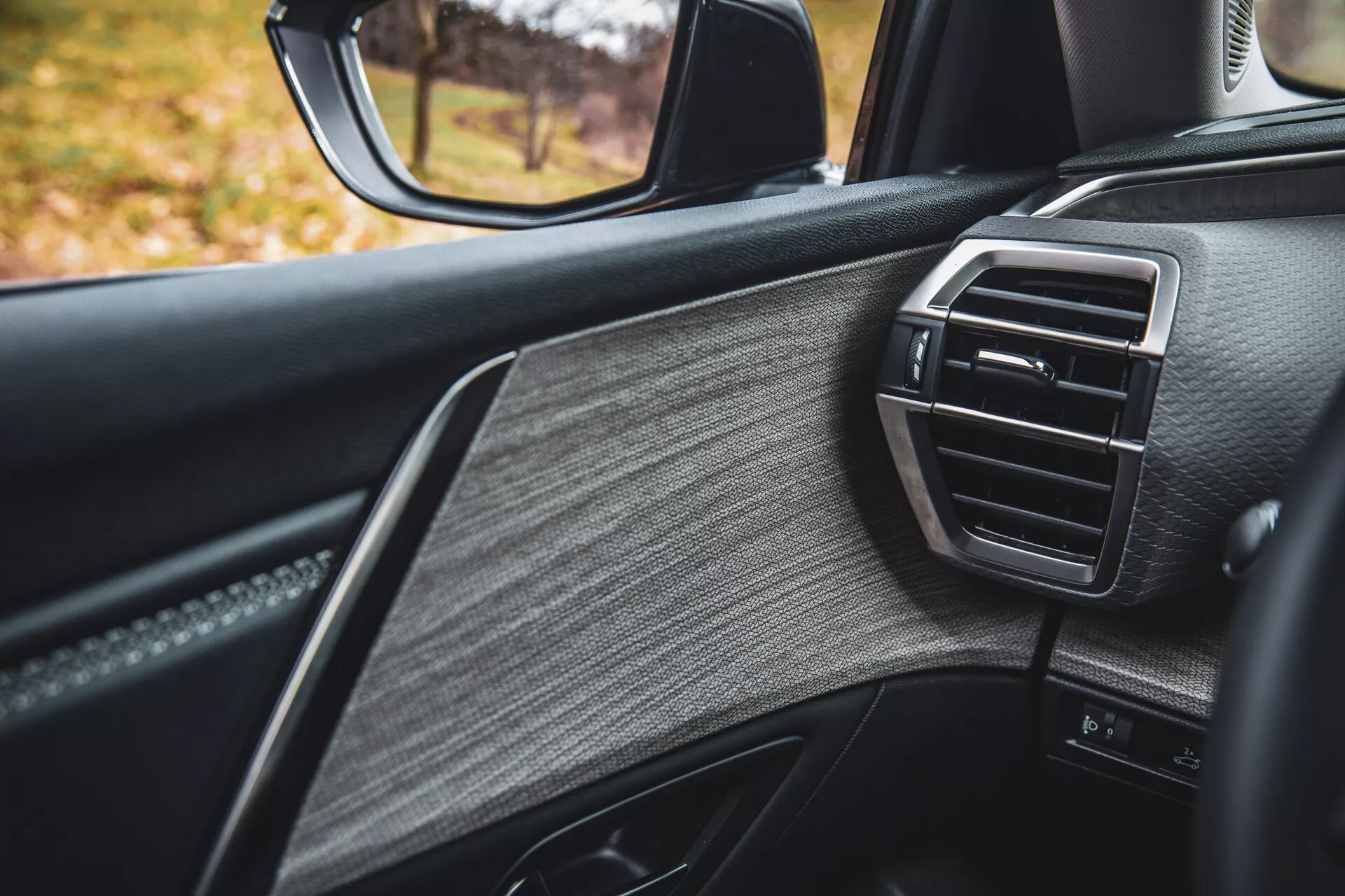 Detailní pohled na dveře na straně spolujezdce Citroen C5-X 2022, předvádějící luxusní design s texturovanou kůží, lesklými ozdobami a ventilační mřížkou klimatizace