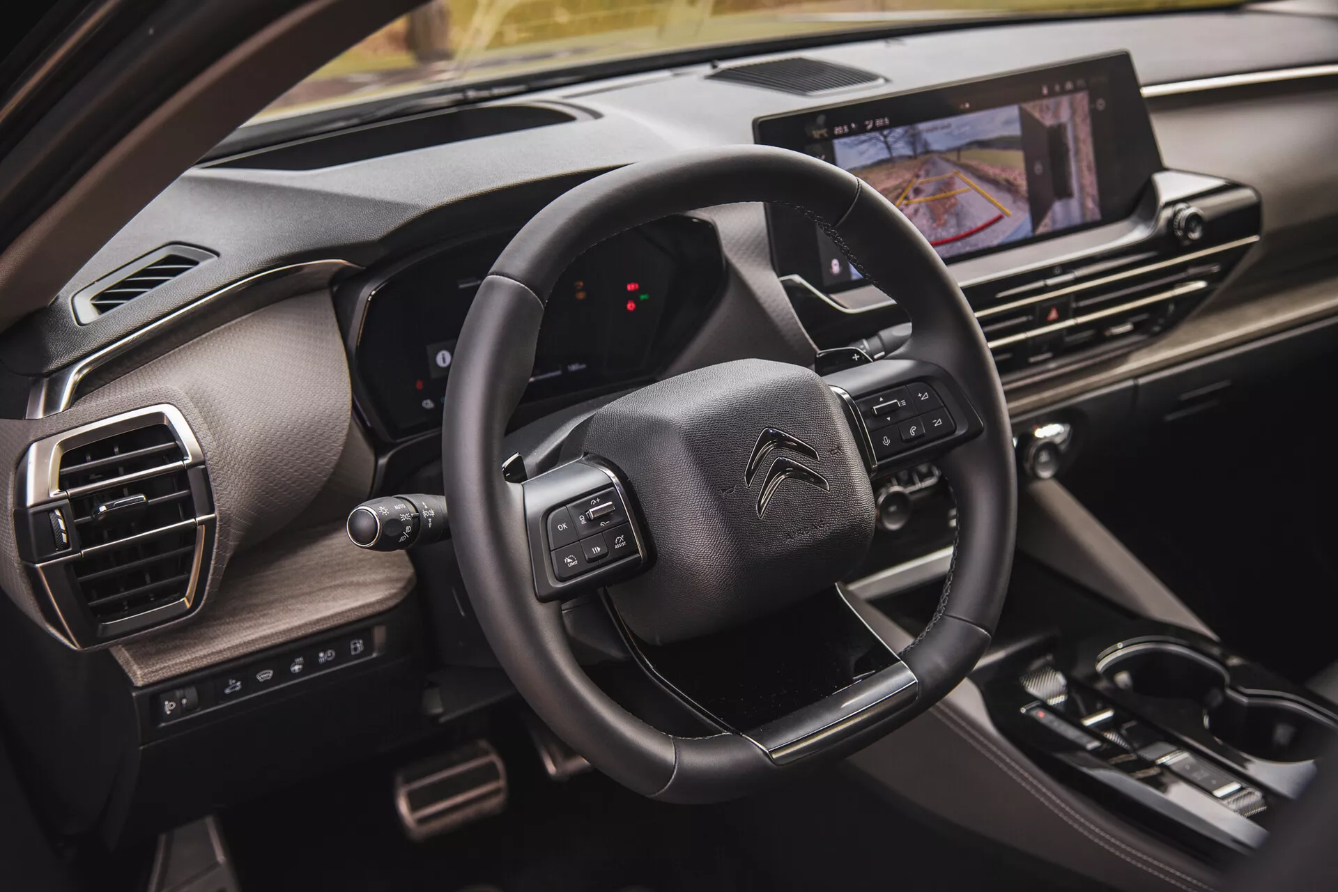 Detailní pohled na interiér Citroën C5-X 2022, který ukazuje volant s multifunkčními tlačítky, digitální displej přístrojové desky z perspektivy spolujezdce a dotykový informačně-zábavní systém
