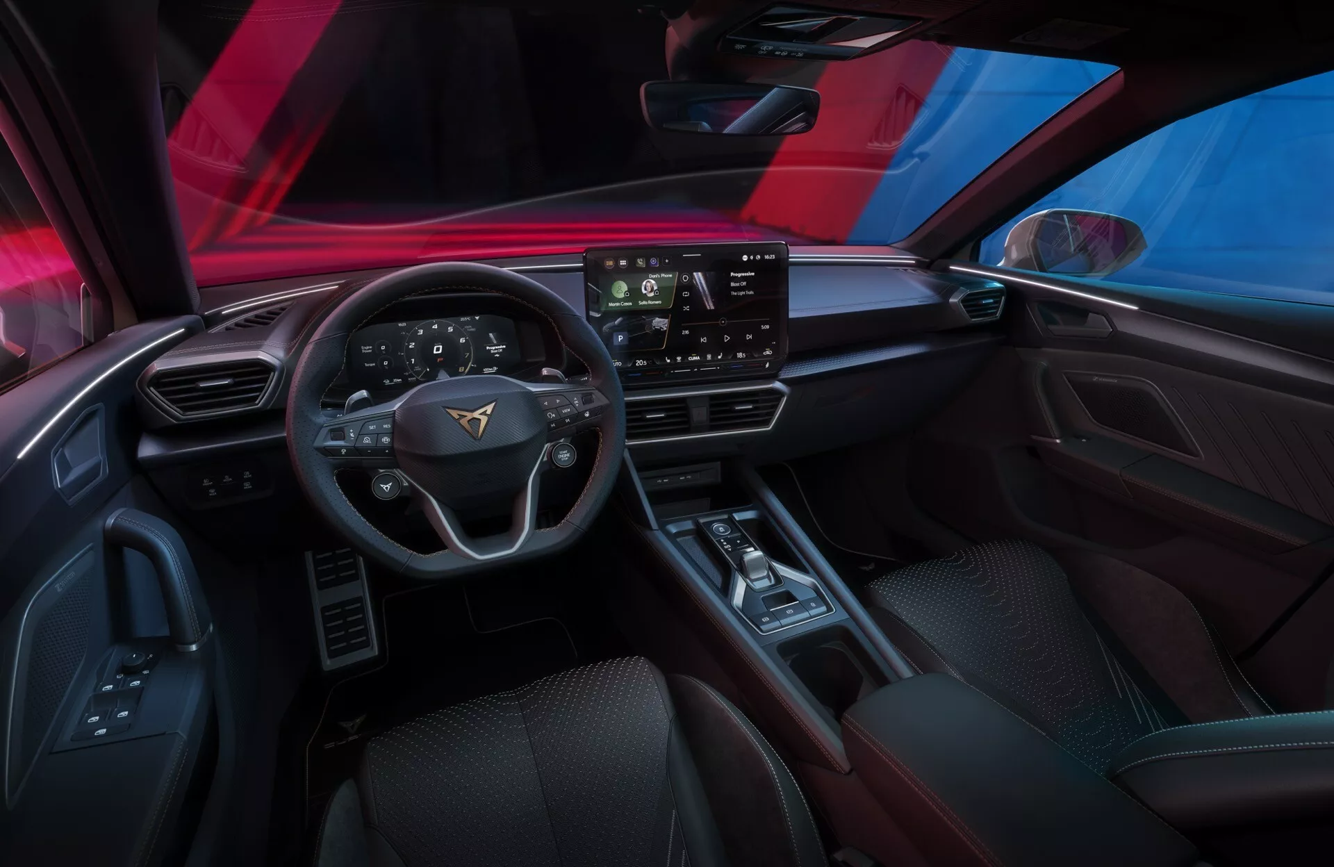 Pohled na interiér modelu Cupra Leon 2024 (1. generace facelift) z pohledu řidiče, ukazující palubní desku, tříramenný volant s integrovanými ovladači, velký dotykový infotainment displej a středovou konzolu. Viditelné funkce zahrnují ovladače oken a zrcátek, reproduktor, digitální přístrojovou desku nebo head-up displej, minimalizovaný ovládací systém klimatizace a pokročilé technologie pro pohodlí, zábavu a asistenci řidiče.