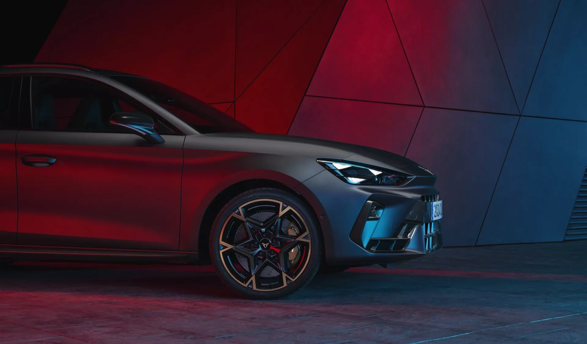 Přední tříčtvrteční pohled na Cupra Leon 2024 (1. generace facelift) zvýrazňující moderní design s LED světlomety, sportovní mřížkou, tvarovaným předním nárazníkem, úhlovými vzduchovými vstupy, vícelúčovými hliníkovými koly a nízkoprofilovými pneumatikami na červeném abstraktním pozadí.