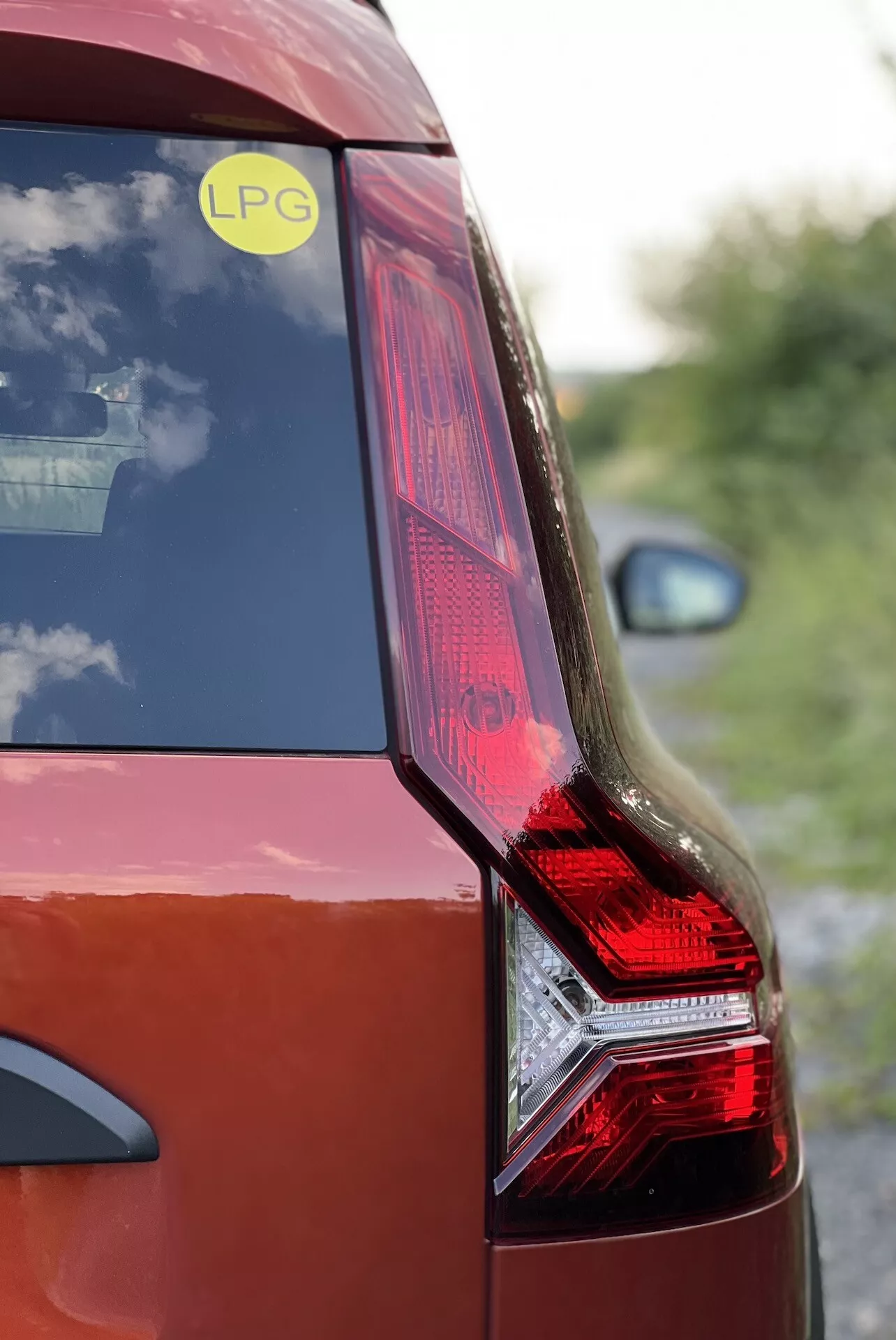 Detailní pohled na zadní stranu Dacia Jogger 2022 s LED zadním světlem, tělem tmavě červené barvy a odznakem LPG, zdůrazňující design vozu a technologii alternativního paliva.
