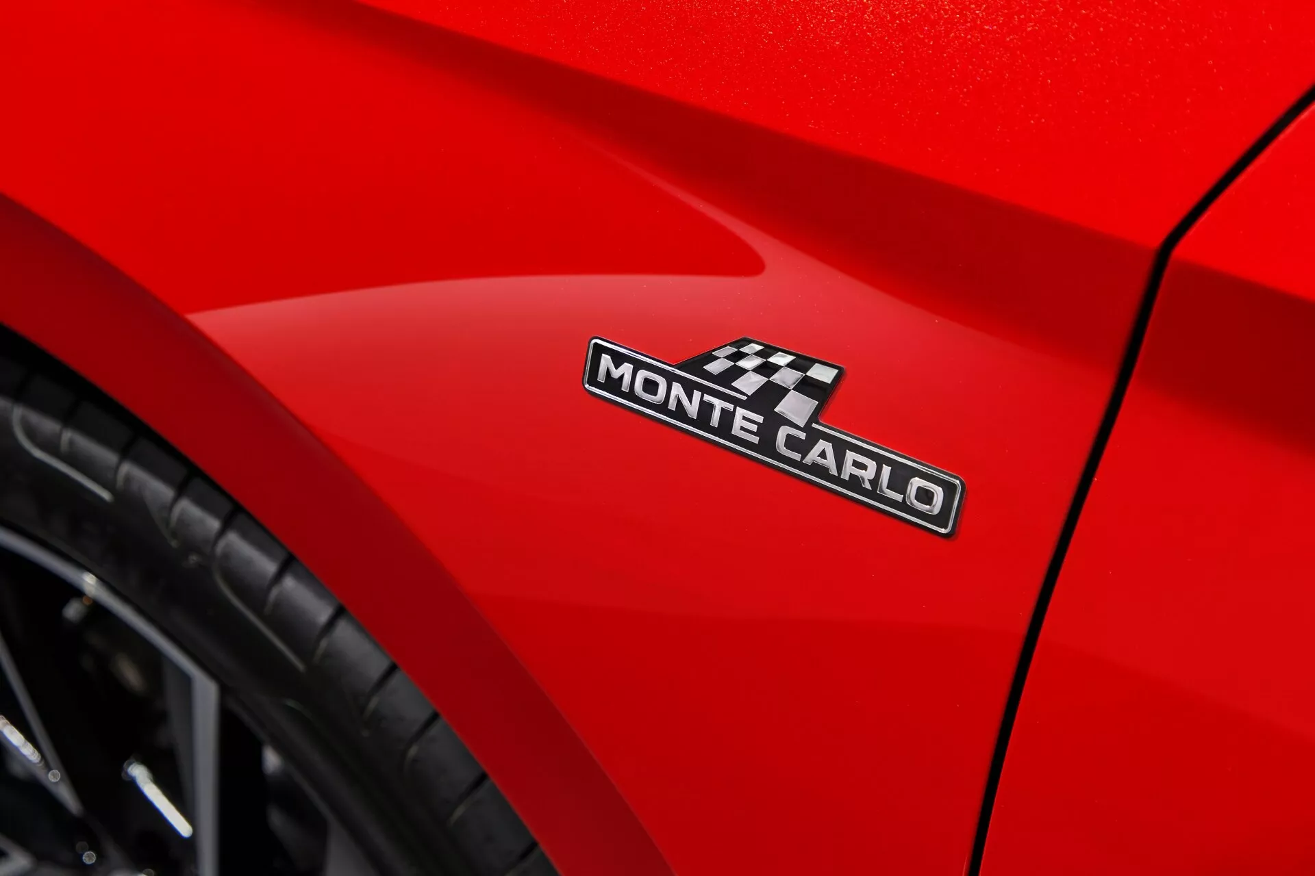 Detailní pohled na Dacia Sandero Stepway 2020 s jasně červenou karoserií zaměřený na emblém MONTE CARLO a elegantní křivku u zadního kola, pořízený z nízkého úhlu